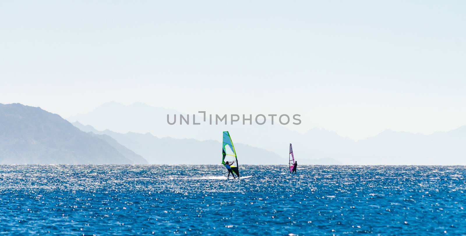 surfers ride in the Red Sea in Egypt against the backdrop of the rocky coast