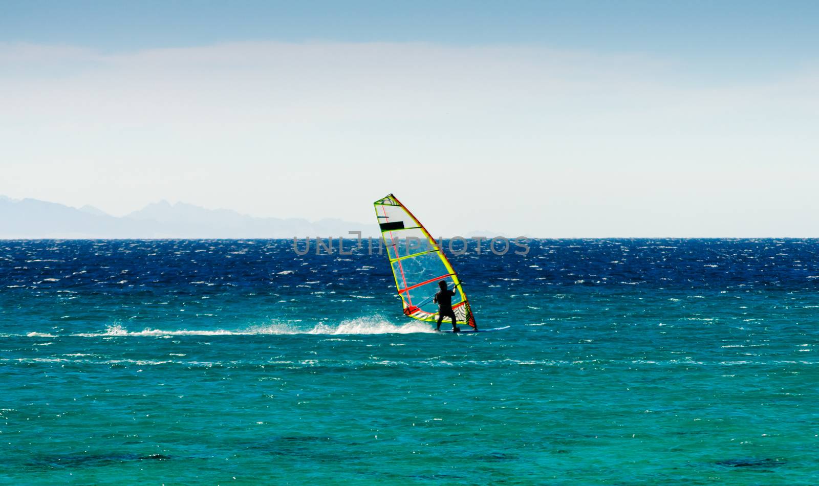 windsurfer on the background of mountains rides on the waves of the Red Sea in Egypt Dahab