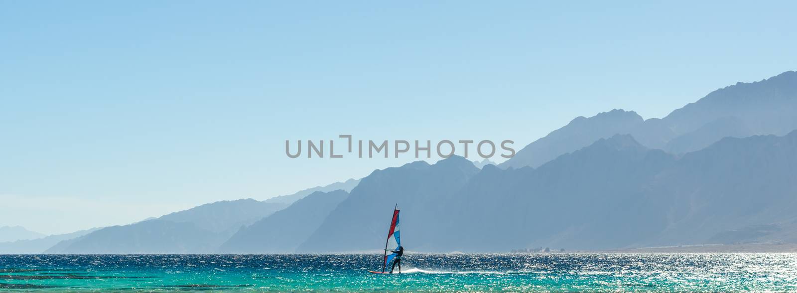 windsurfer rides in the Red Sea against the backdrop of high rocky mountains in Egypt