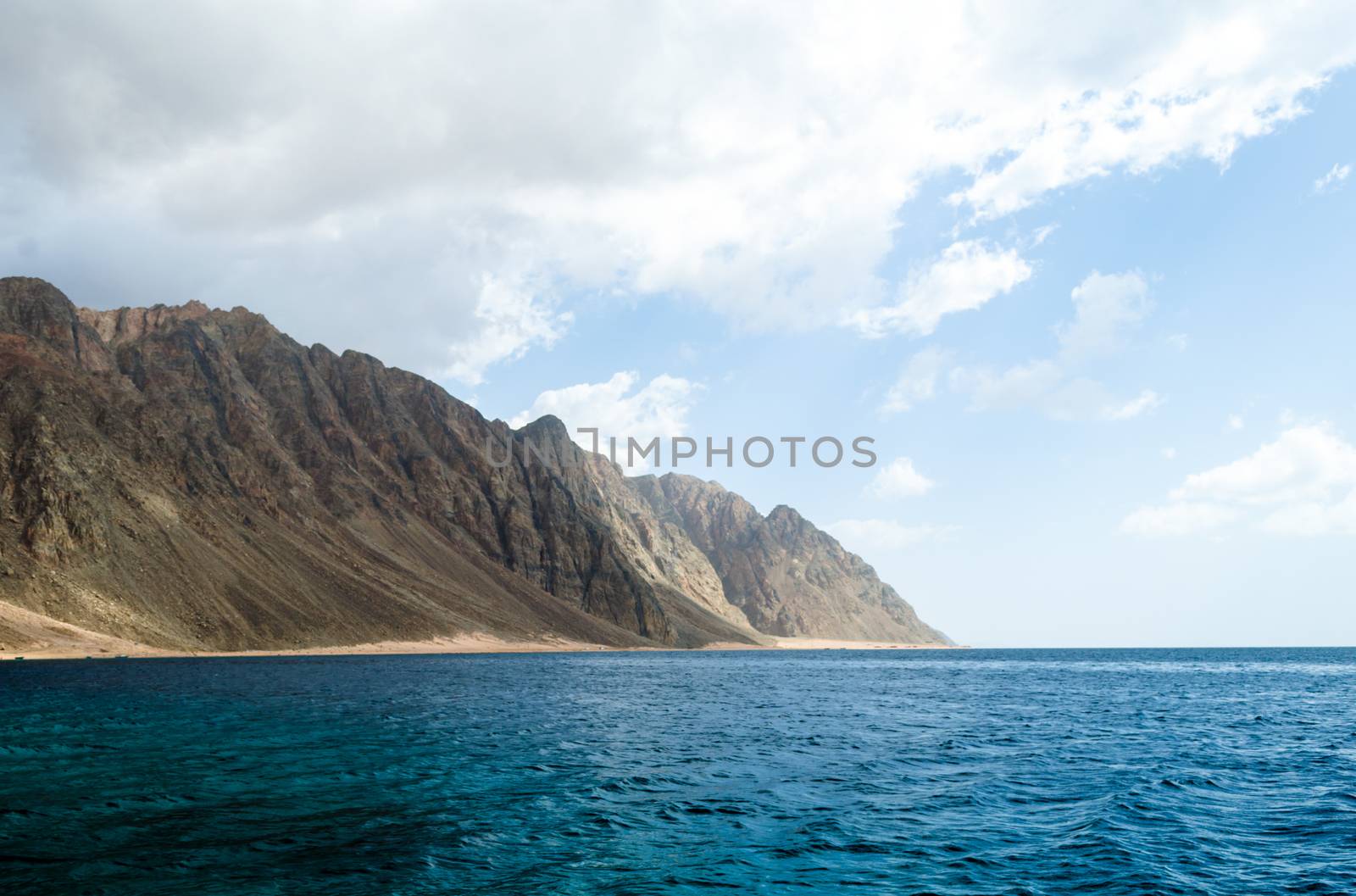 blue sea and high rocky mountains against the sky and clouds in Egypt Dahab