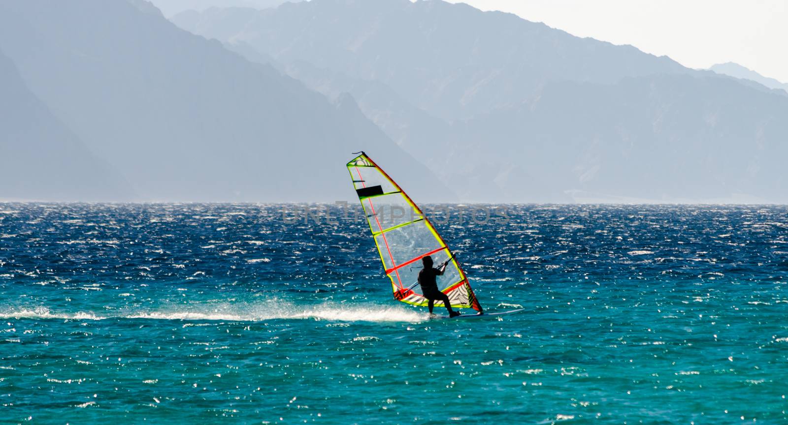 windsurfer on the background of high mountains rides on the waves of the Red Sea in Egypt Dahab