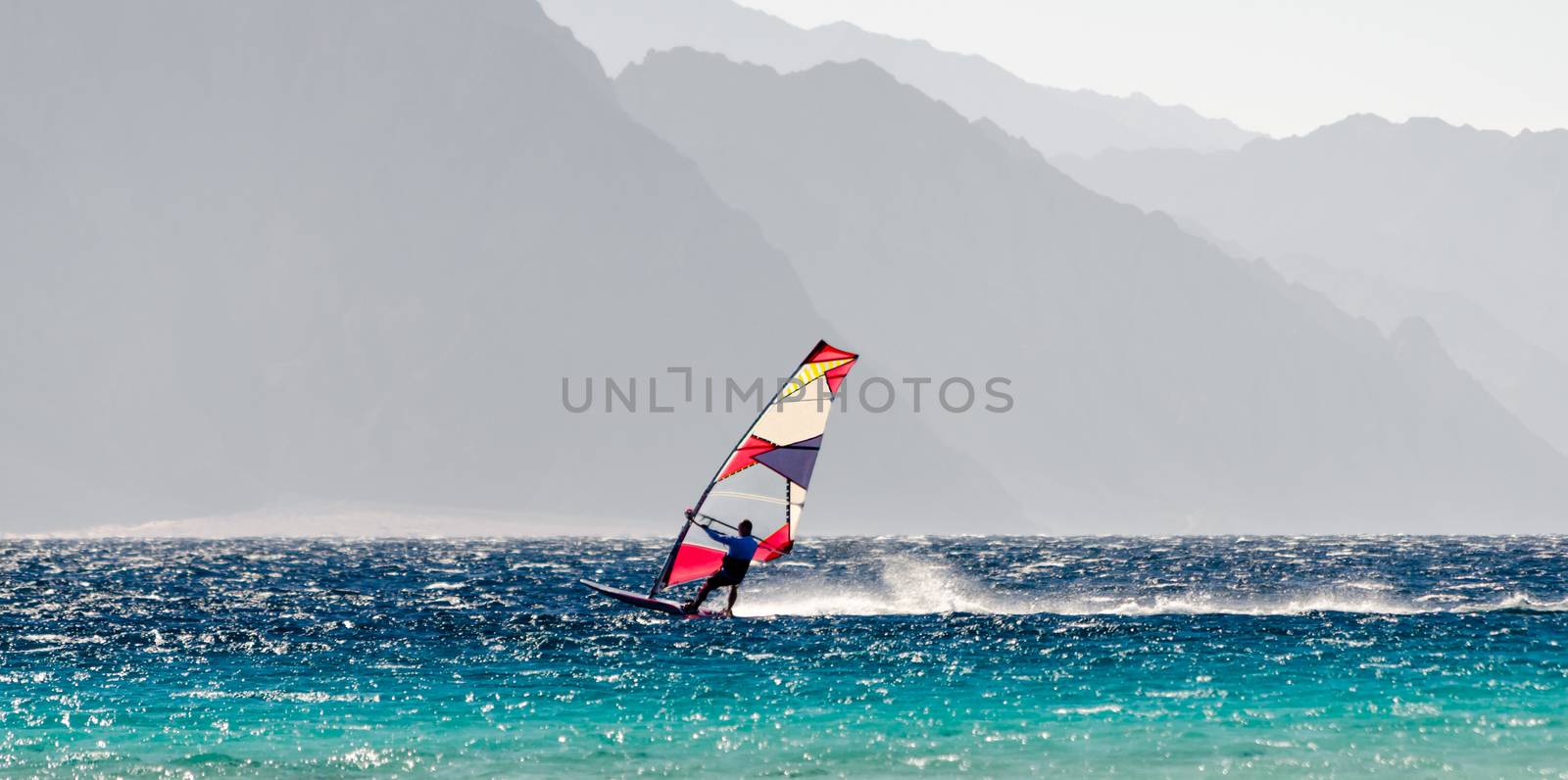 windsurfer rides on a background of high rocky mountains in Egypt Dahab