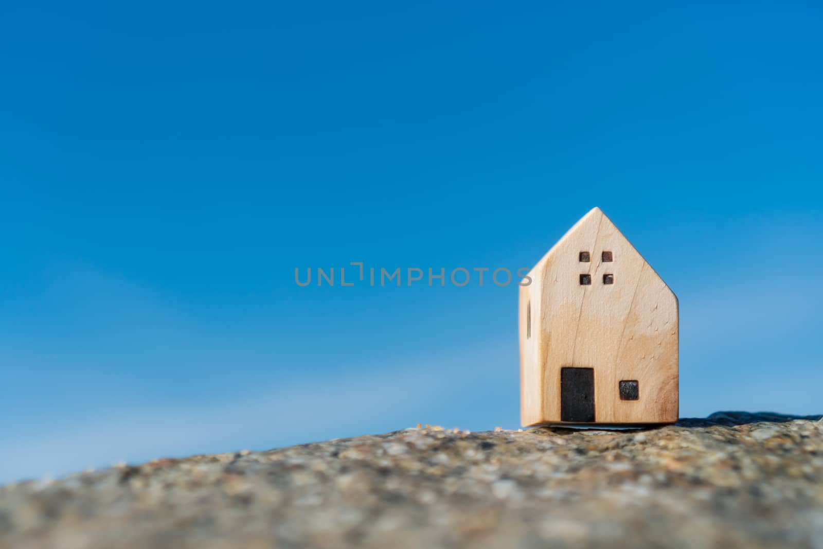 Model of a little house on sand with nature beach background. Dream life concept.