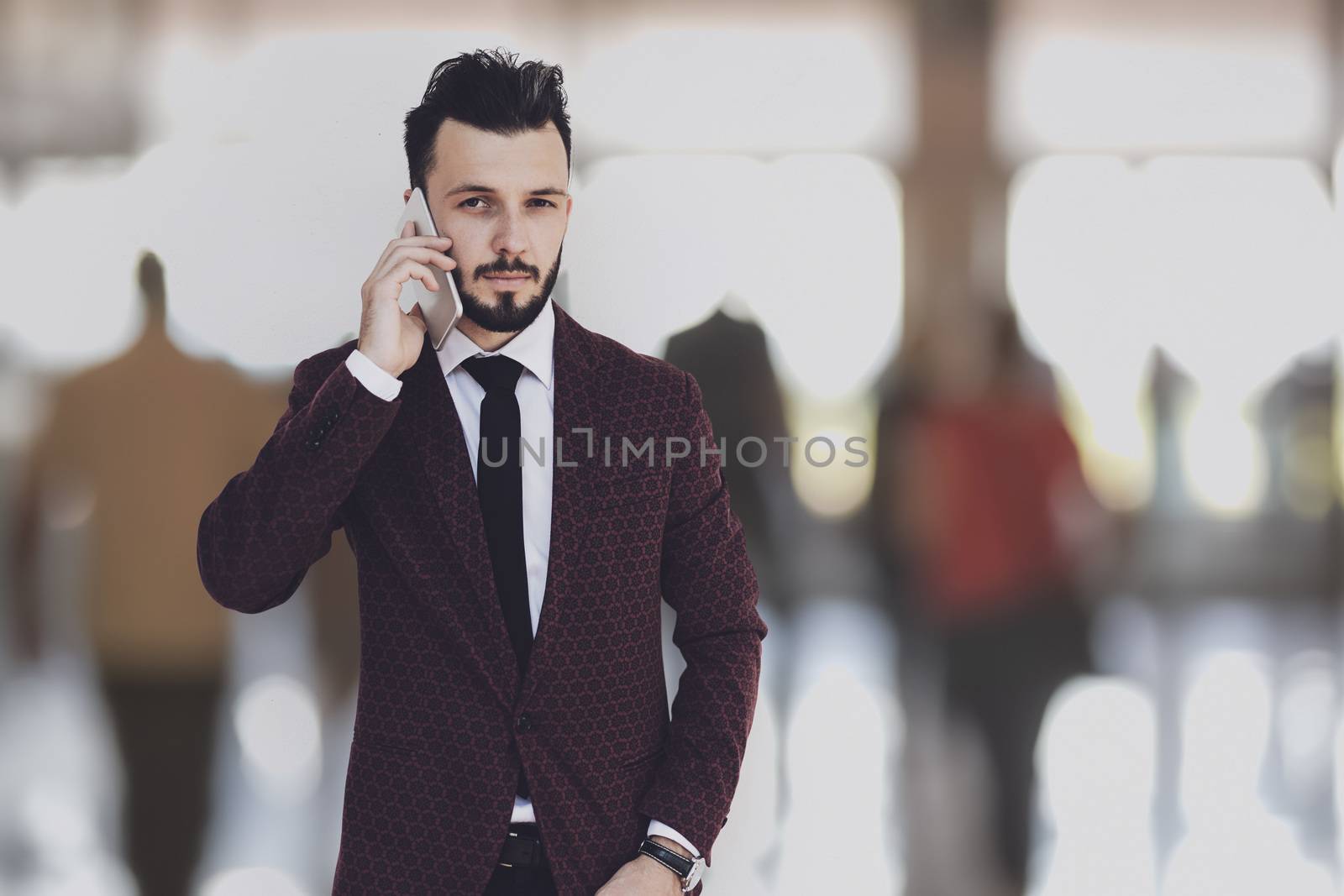 Global communication concept - businessman posing on a blured background of business people and talking on the phone.