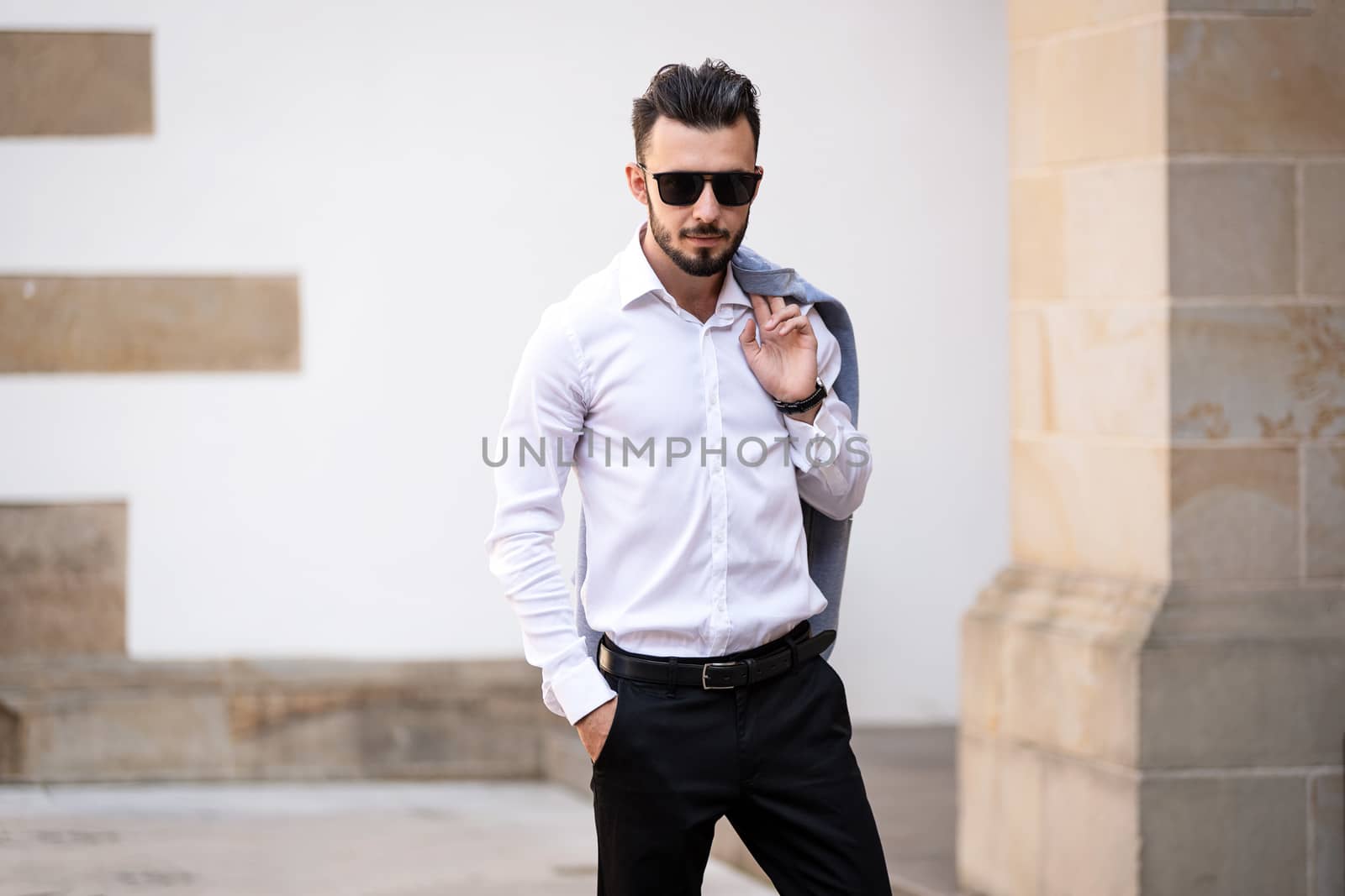 Portrait of elegant and fashionable man in black sunglasses posing on the street
