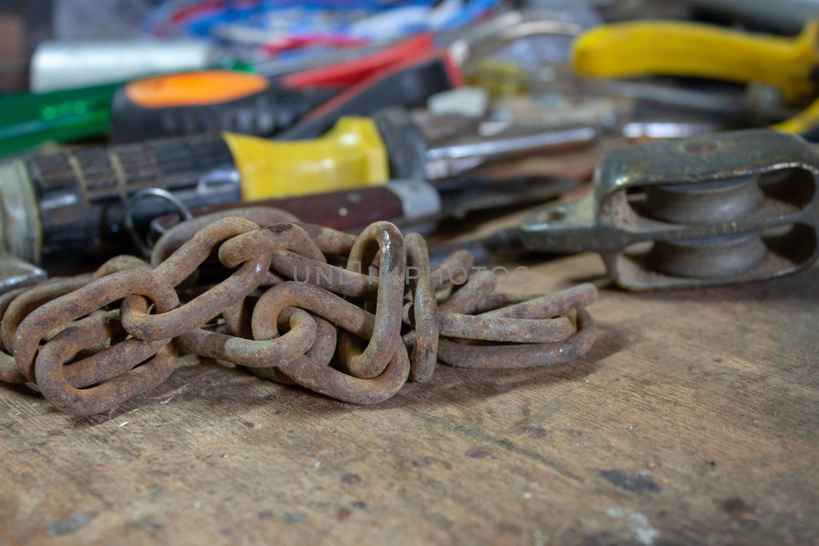 Table of a mechanical and electrician workshop, with an old chain and another tools on top by etcho