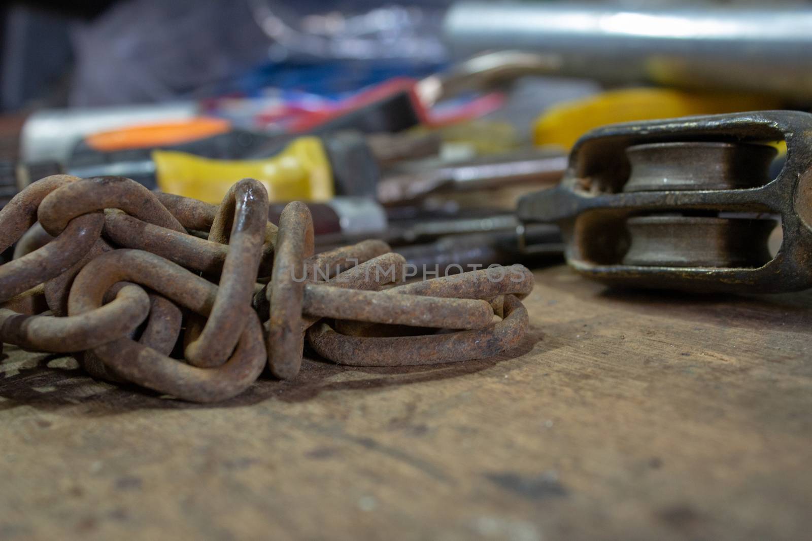 Table of a mechanical and electrician workshop, with an old chain and another tools on top by etcho