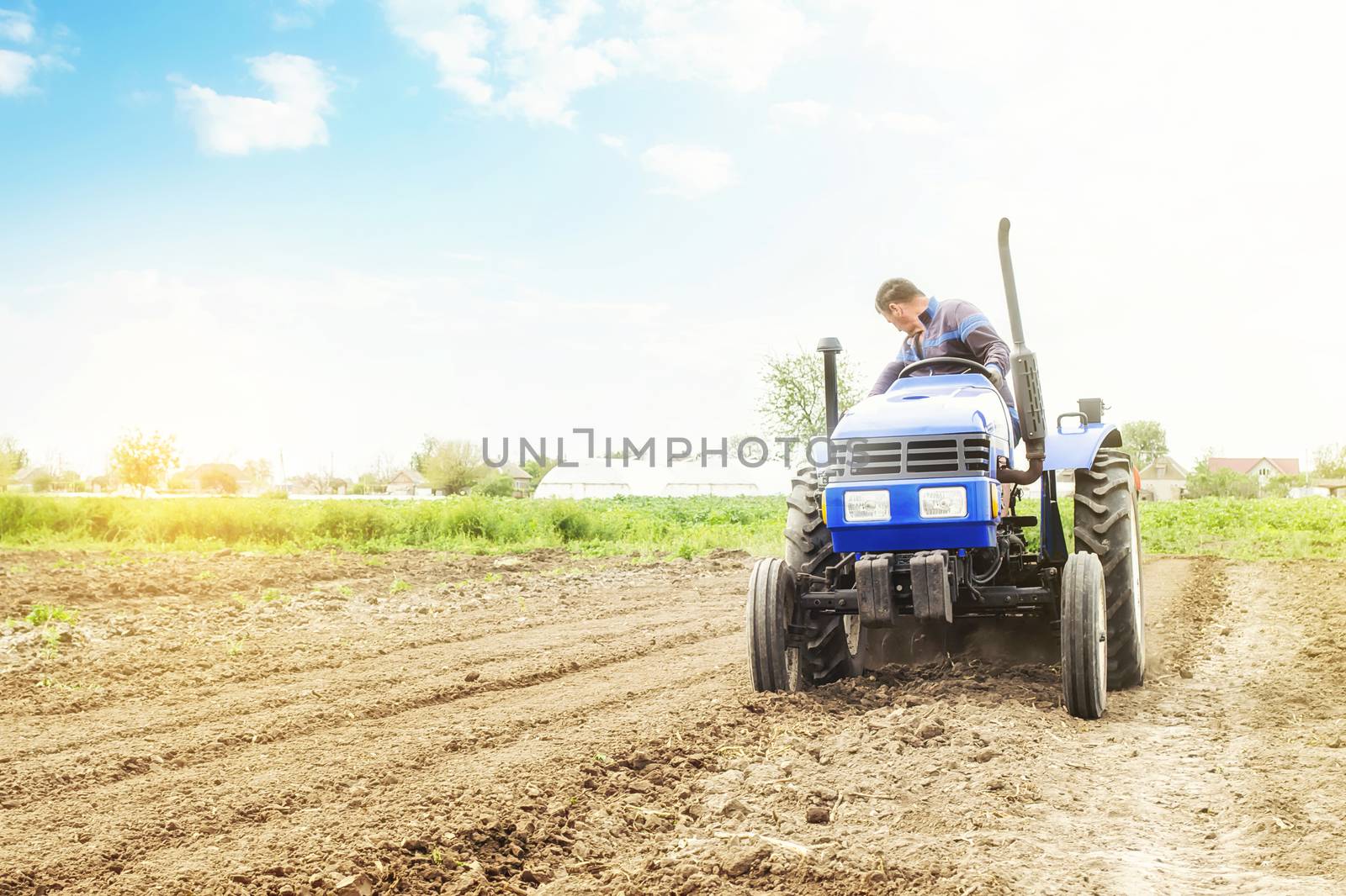 Farmer on a tractor with milling machine loosens, grinds and mixes soil. Loosening surface, cultivating the land for further planting. Farming and agriculture. Use of agricultural machinery on a farm. by iLixe48