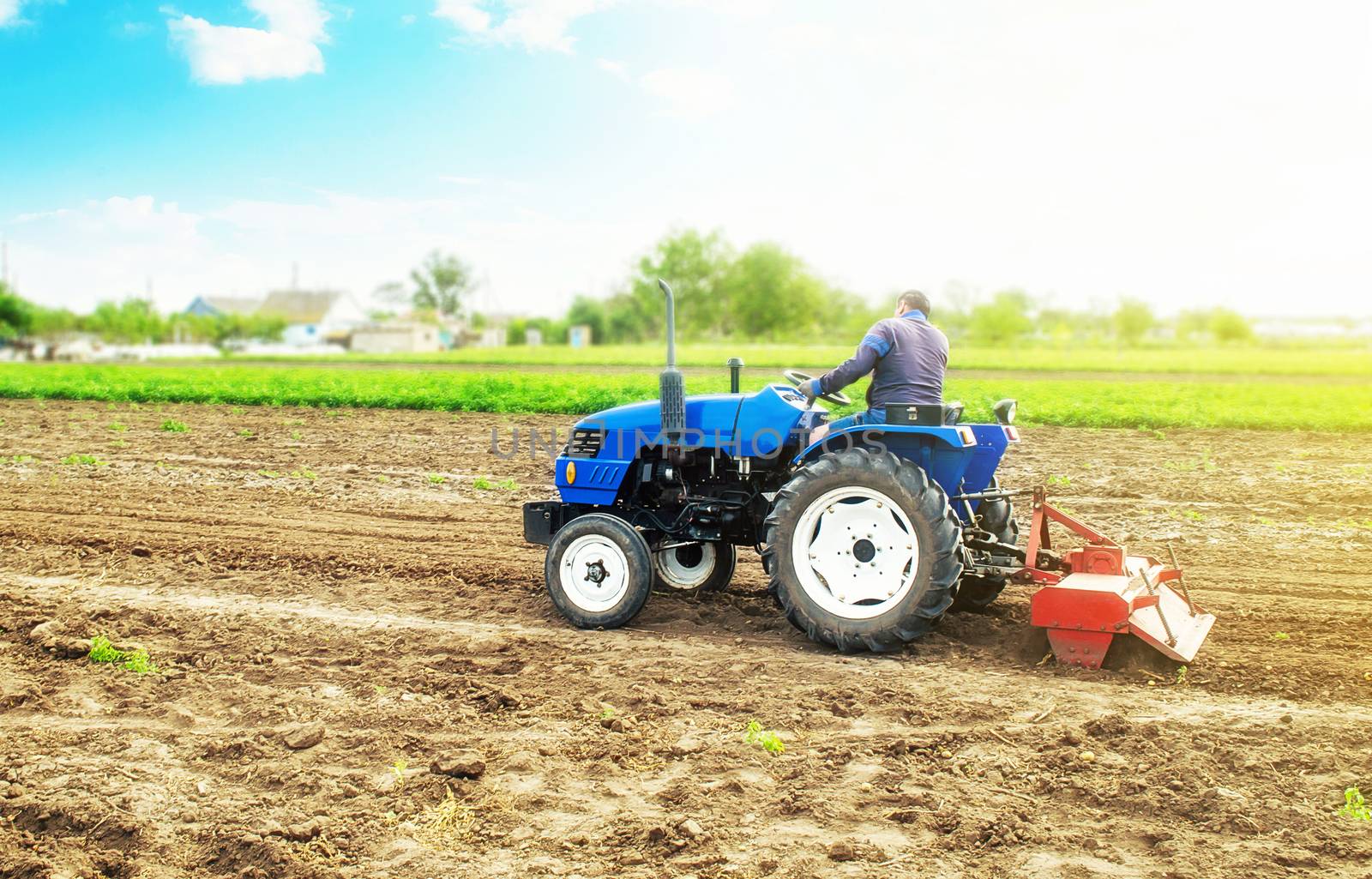 Farmer on a tractor with milling machine loosens, grinds and mixes soil. Field preparation for new crop planting. Work on preparing the soil for a sowing of seeds of agricultural crops. by iLixe48