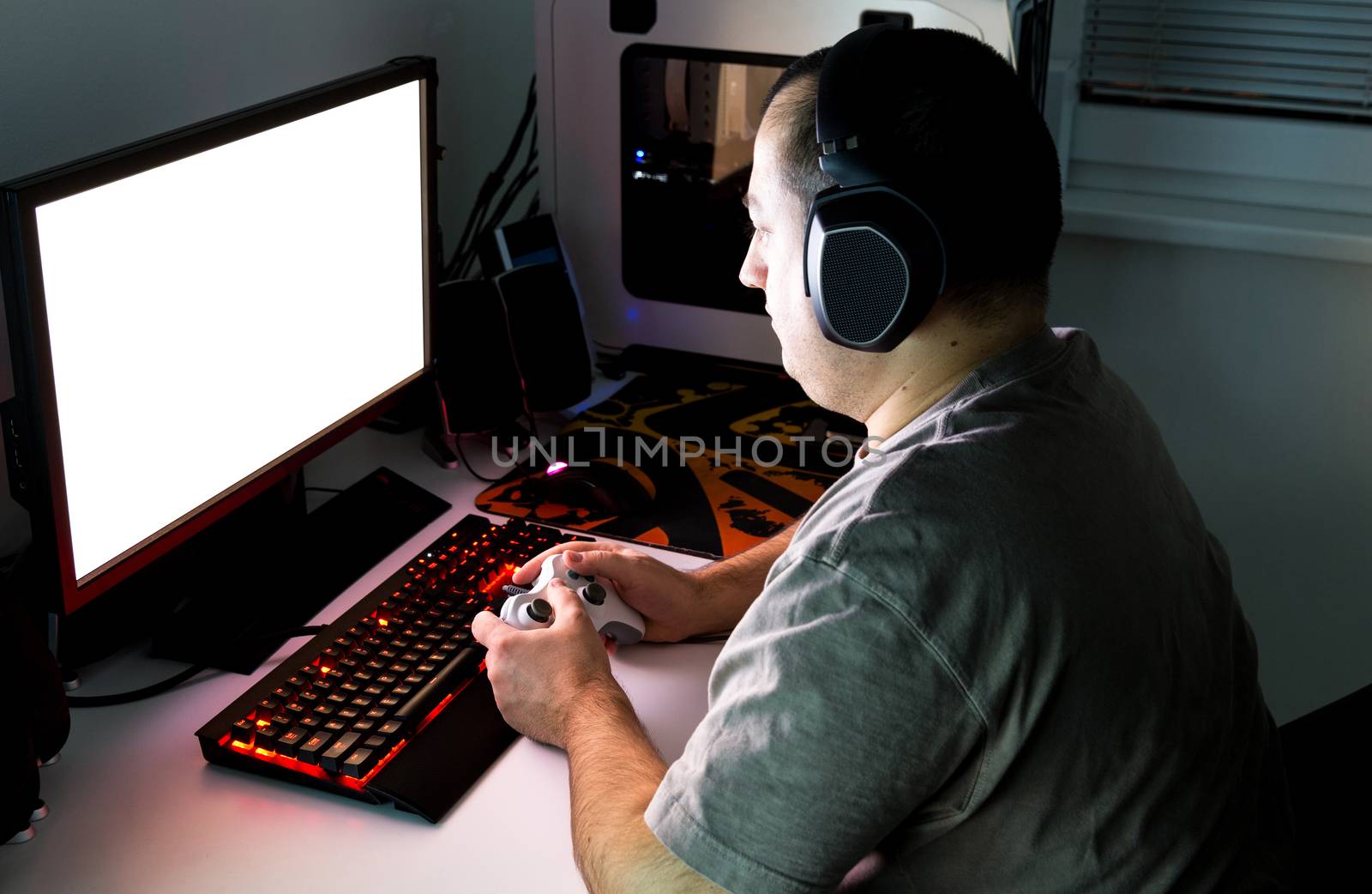 Man playing computer game on custom made desktop with joypad, keyboard, mouse.