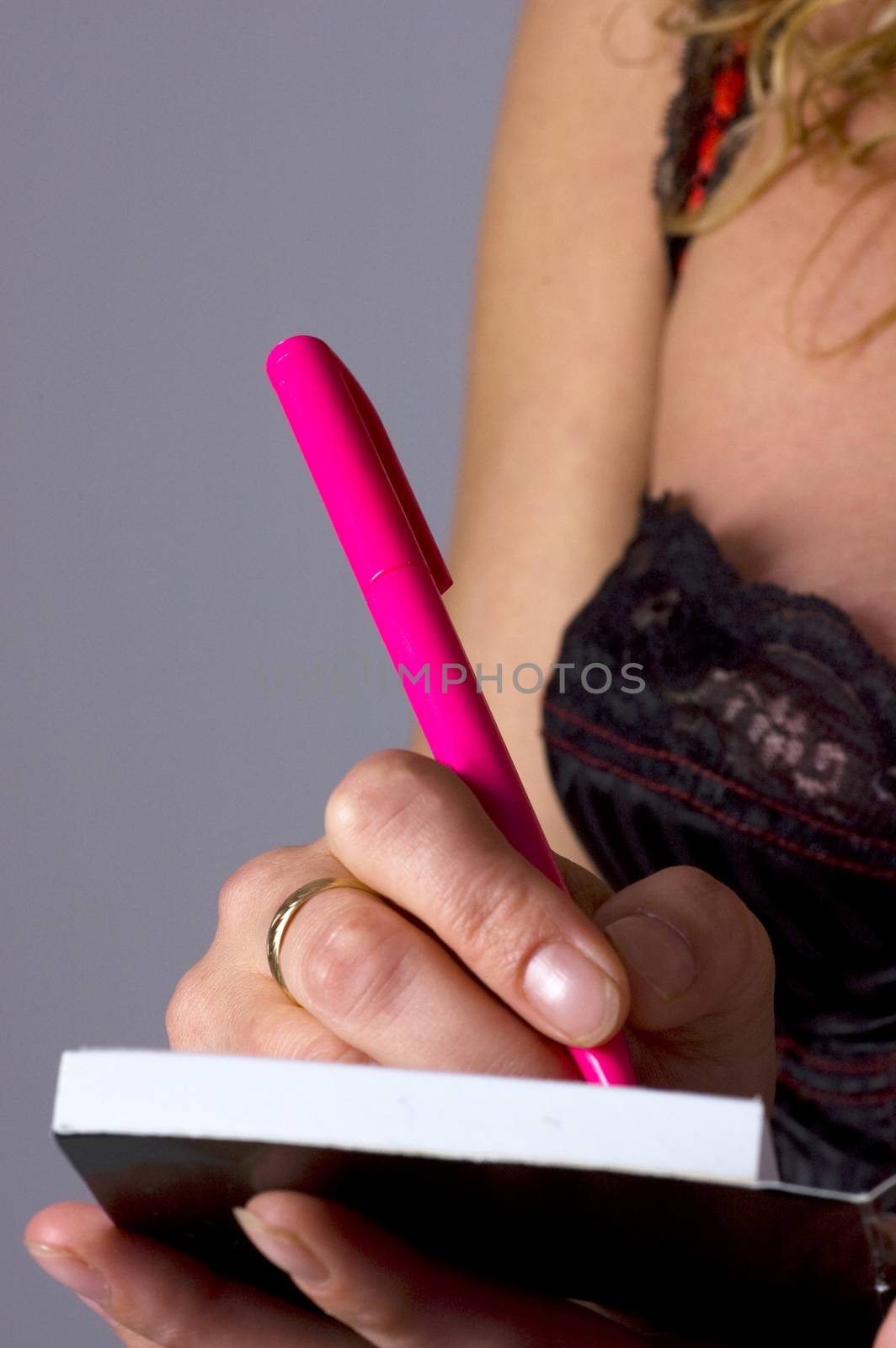 Sexy young secretary writing in notebook with pink pen