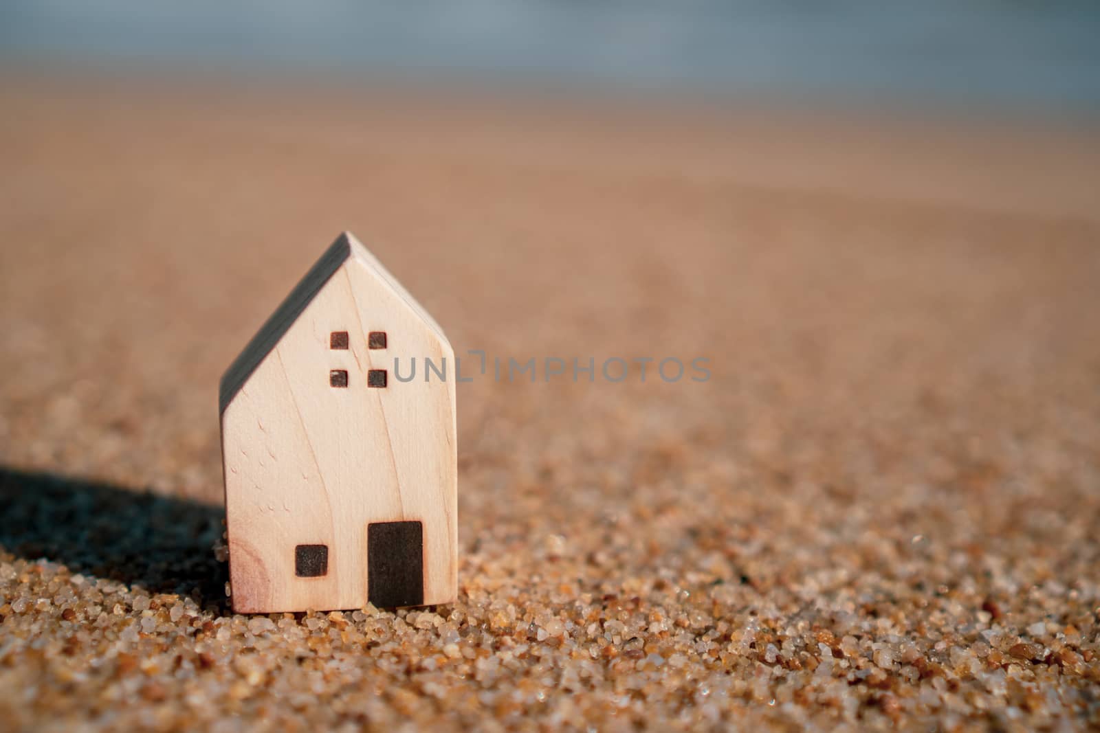 Model of a little house on sand with nature beach background. Dream life concept.