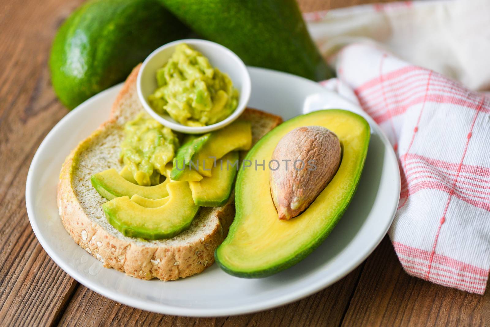 Avocado sliced half and avocado dip mashed on white plate background fruits healthy food concept / avocado toast