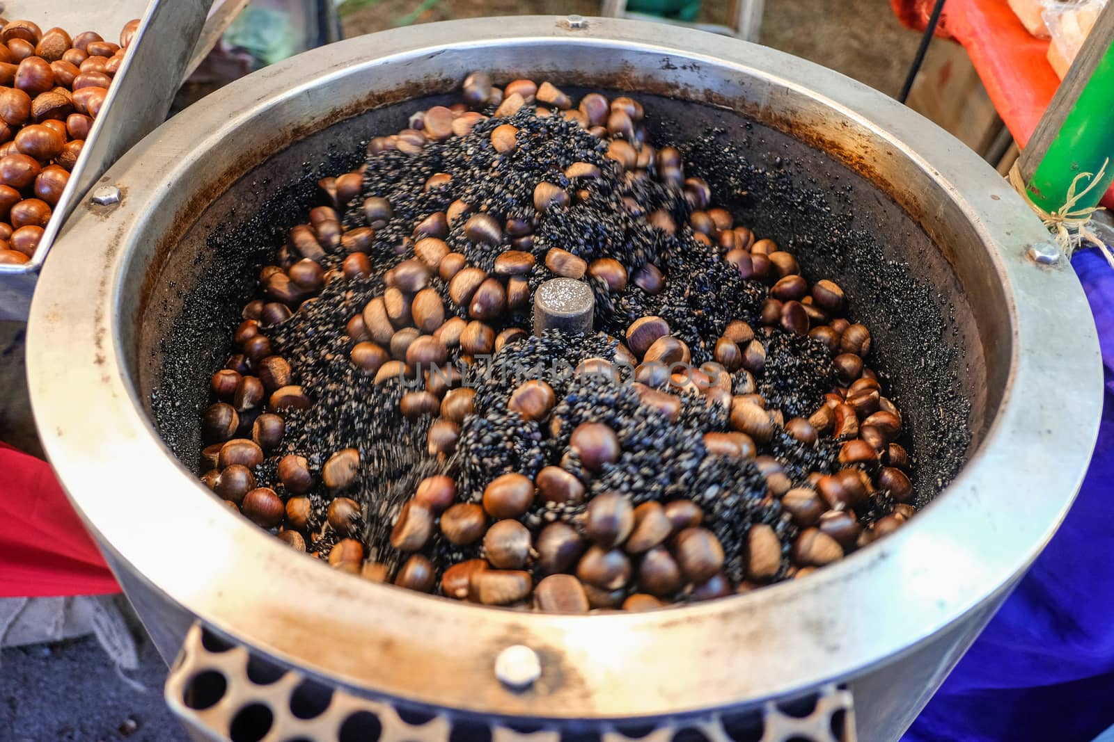 Food market. Roasting brown chestnuts in a big pot.