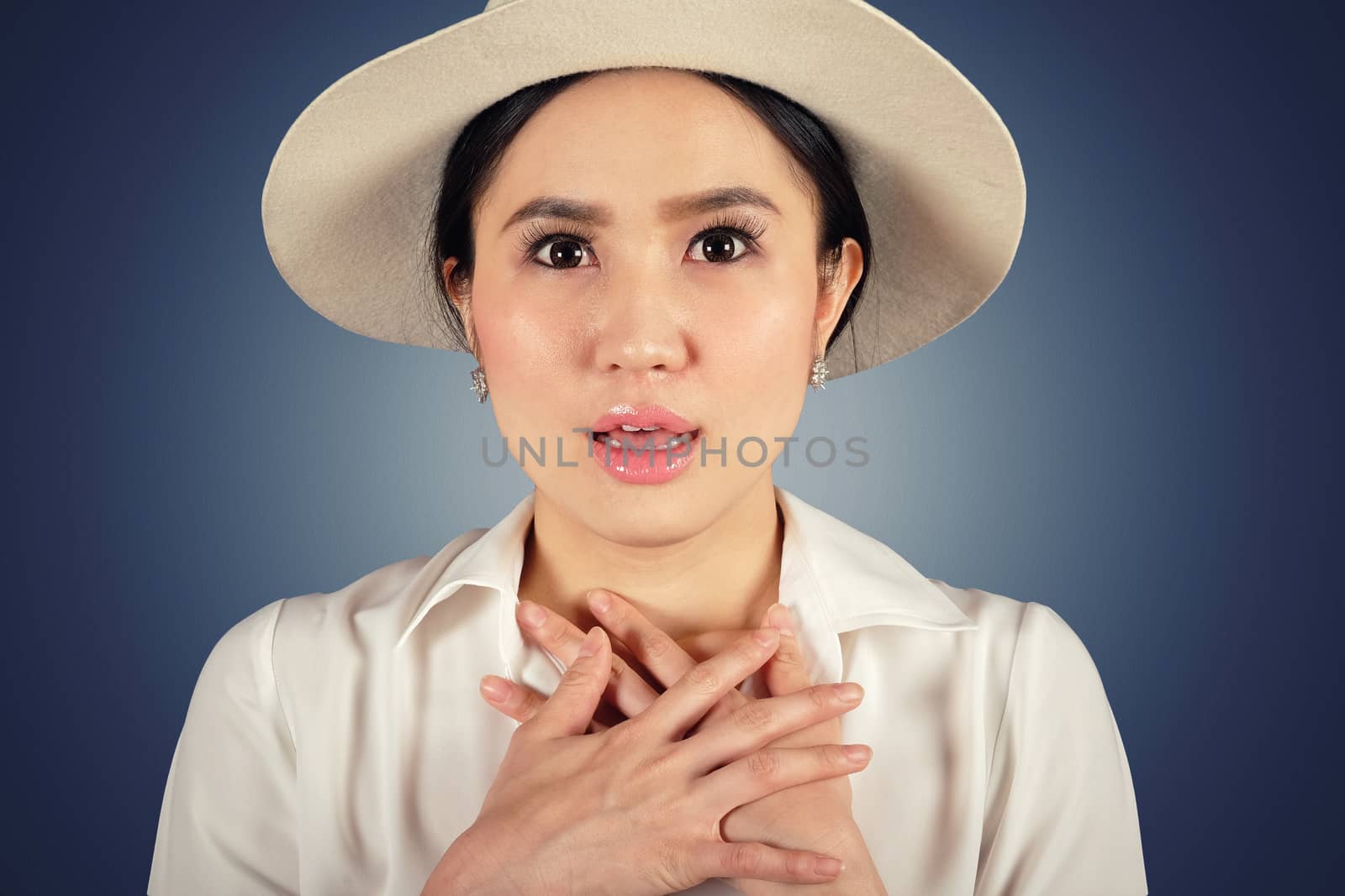 Shocked woman wearing stylish hat looking at camera and dark background