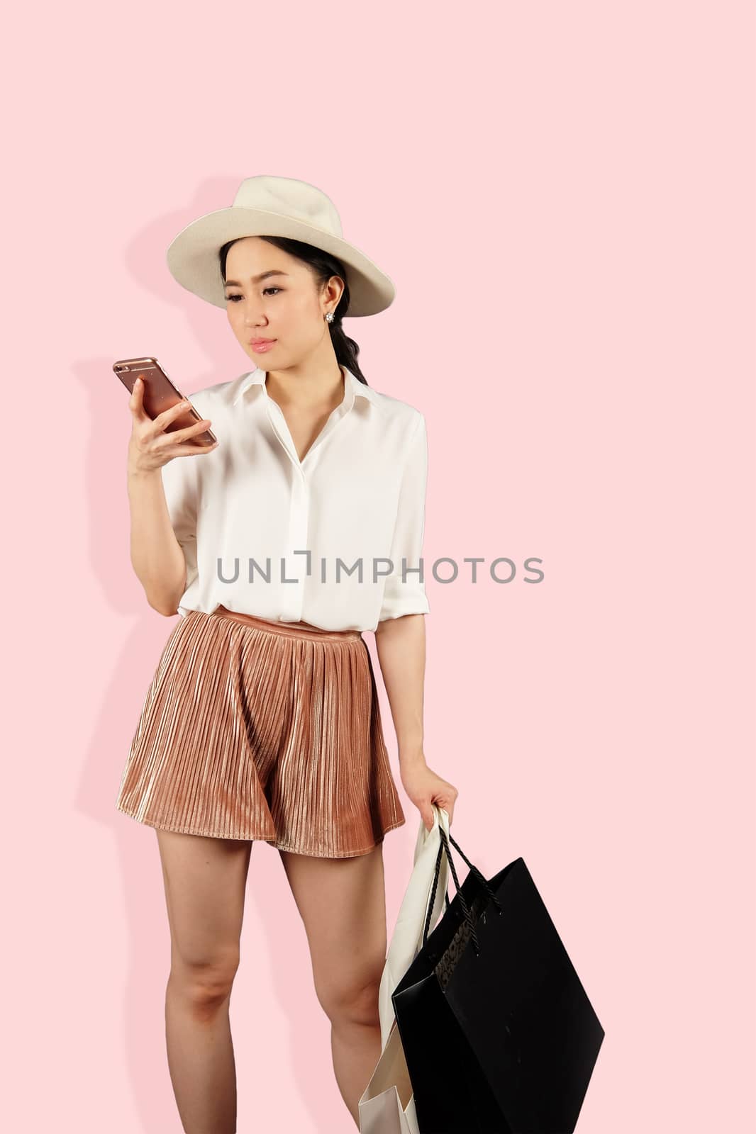 Young asian woman to see a smartphone and hold shopping bag by Surasak