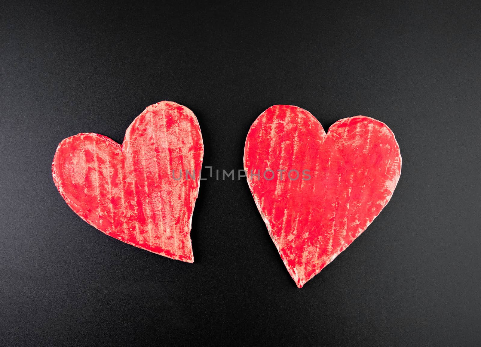 Two red heart-shaped recycled cardboard isolated on a dark background. Concepts of Love and Romance.