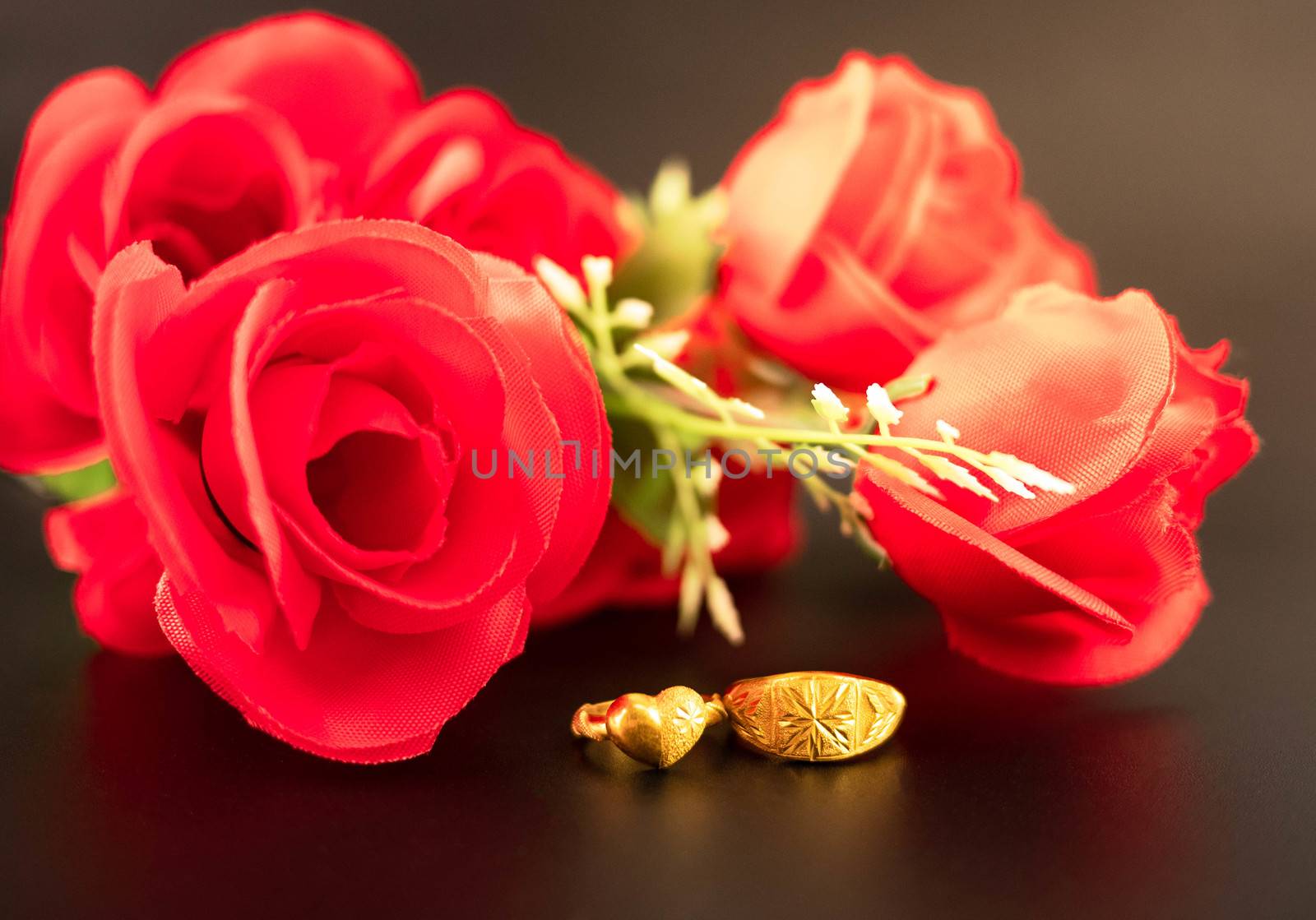 Wedding celebration on valentines day with red rose bouquet, wedding rings, isolated on dark background. Concept of love and romance. by TEERASAK