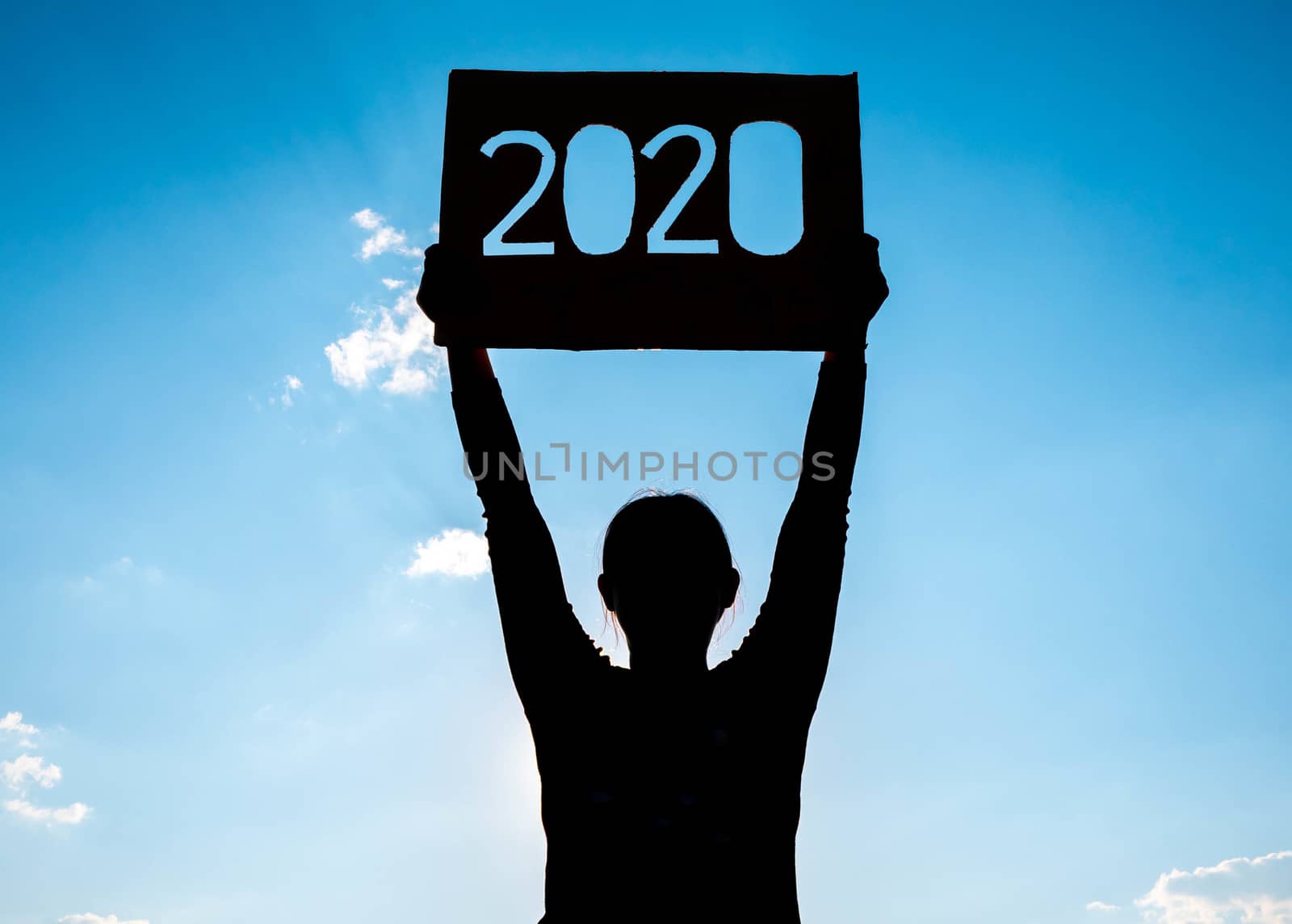 Silhouette of woman holding recycle cardboard with 2020 text over blue sky background and the sunshining through the text. Concepts of New Year and celebration.