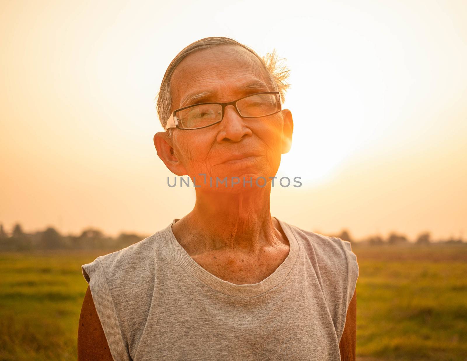 Asian senior man jogging on a sunset background over a field in countryside. Healthcare concept. by TEERASAK