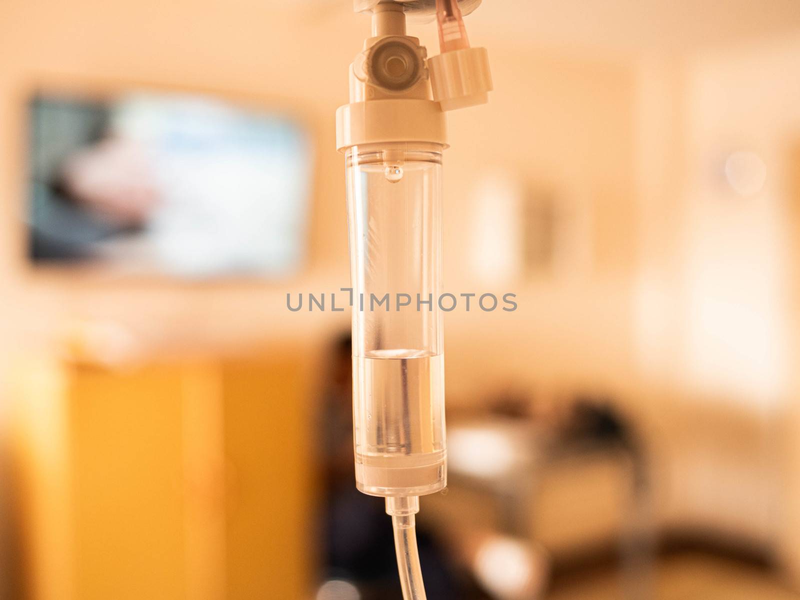 Close-up of Saline solution drip for patient and infusion pump on blurred luxury VIP room background in hospital. by TEERASAK