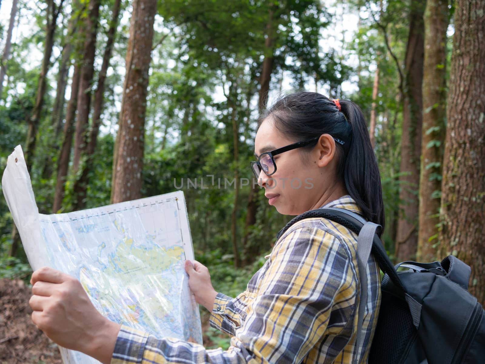 Young woman traveler with map and backpack relaxing outdoor at nYoung woman traveler with map and backpack relaxing outdoor at nature trail on summer vacations day. Lifestyle hiking concept. by TEERASAK