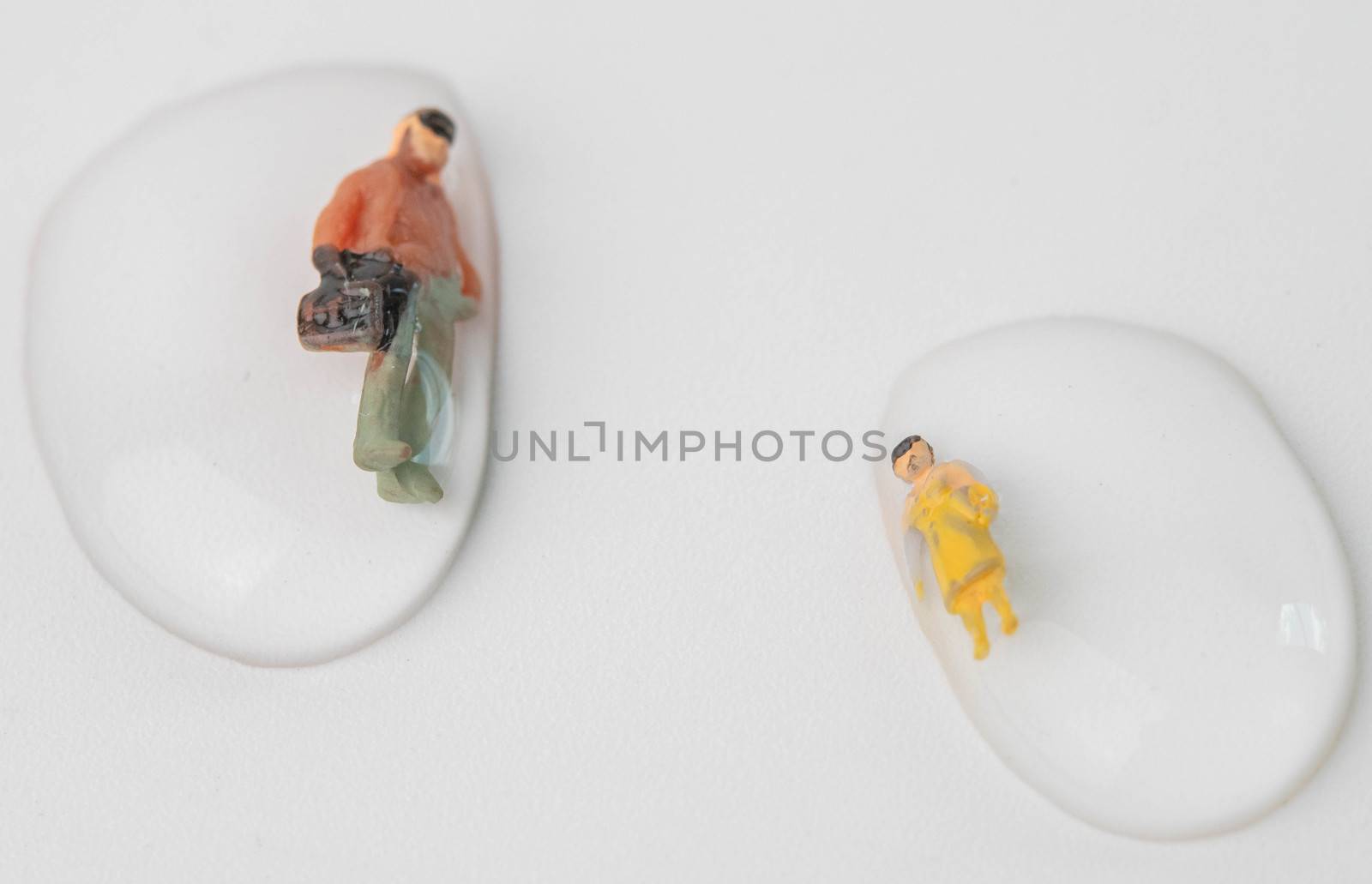 Miniature people get drowned in drops of water on white background. Macro photography concept idea for solution of solving problems in the wrong life.