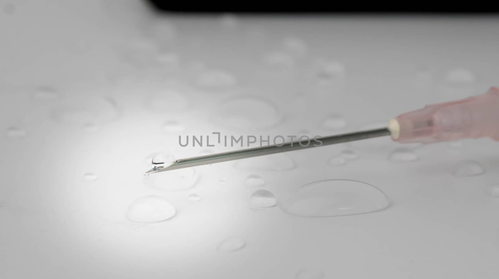 Drops of water with medical equipment syringe needle on white background. Selective focus. by TEERASAK