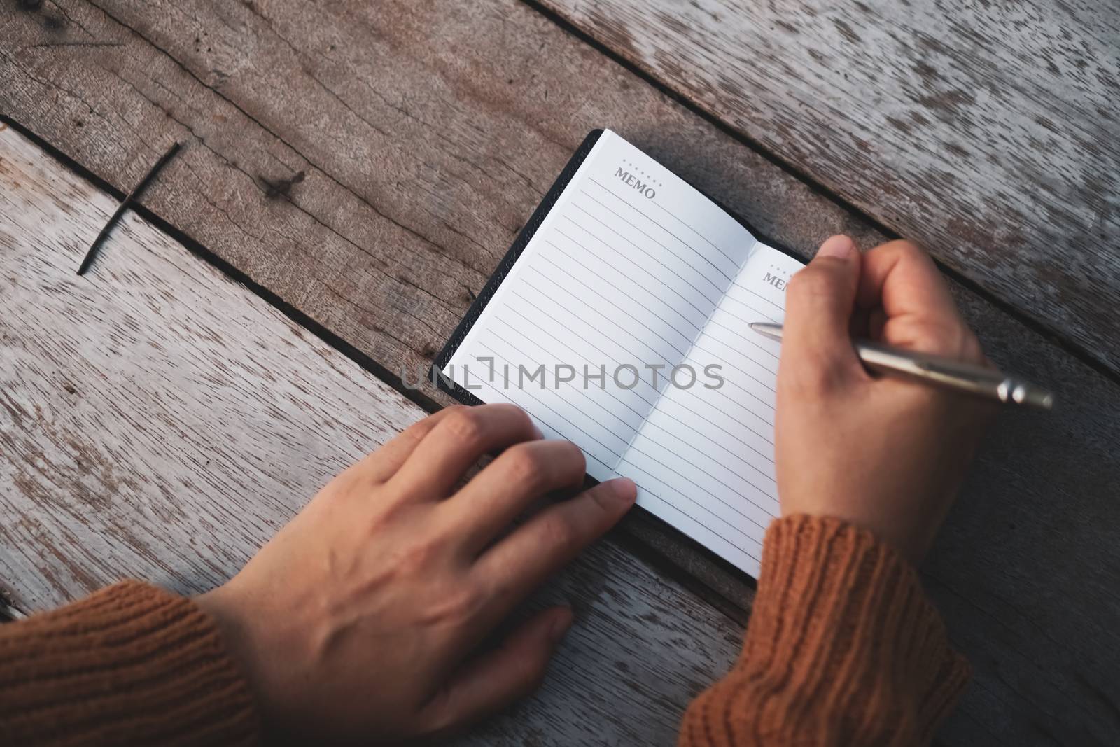 Copy space of woman hand writing down in white notebook with colorful bokeh background.