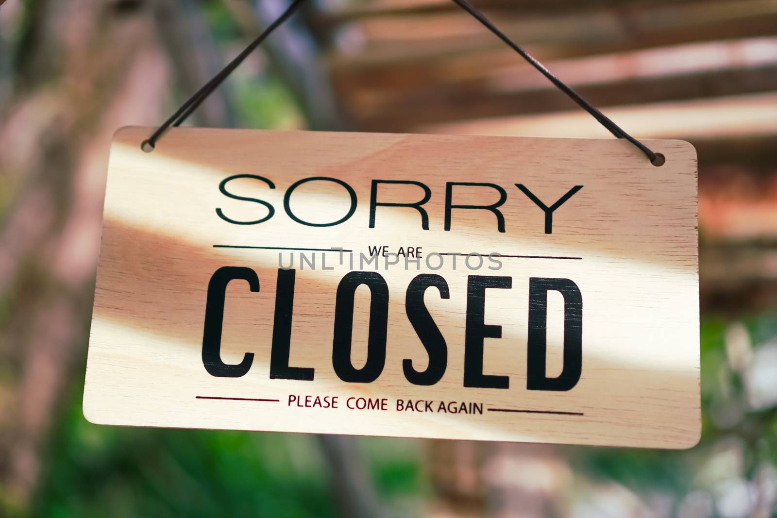 A Sign board of sorry we are closed hang on door of business shop with nature green background