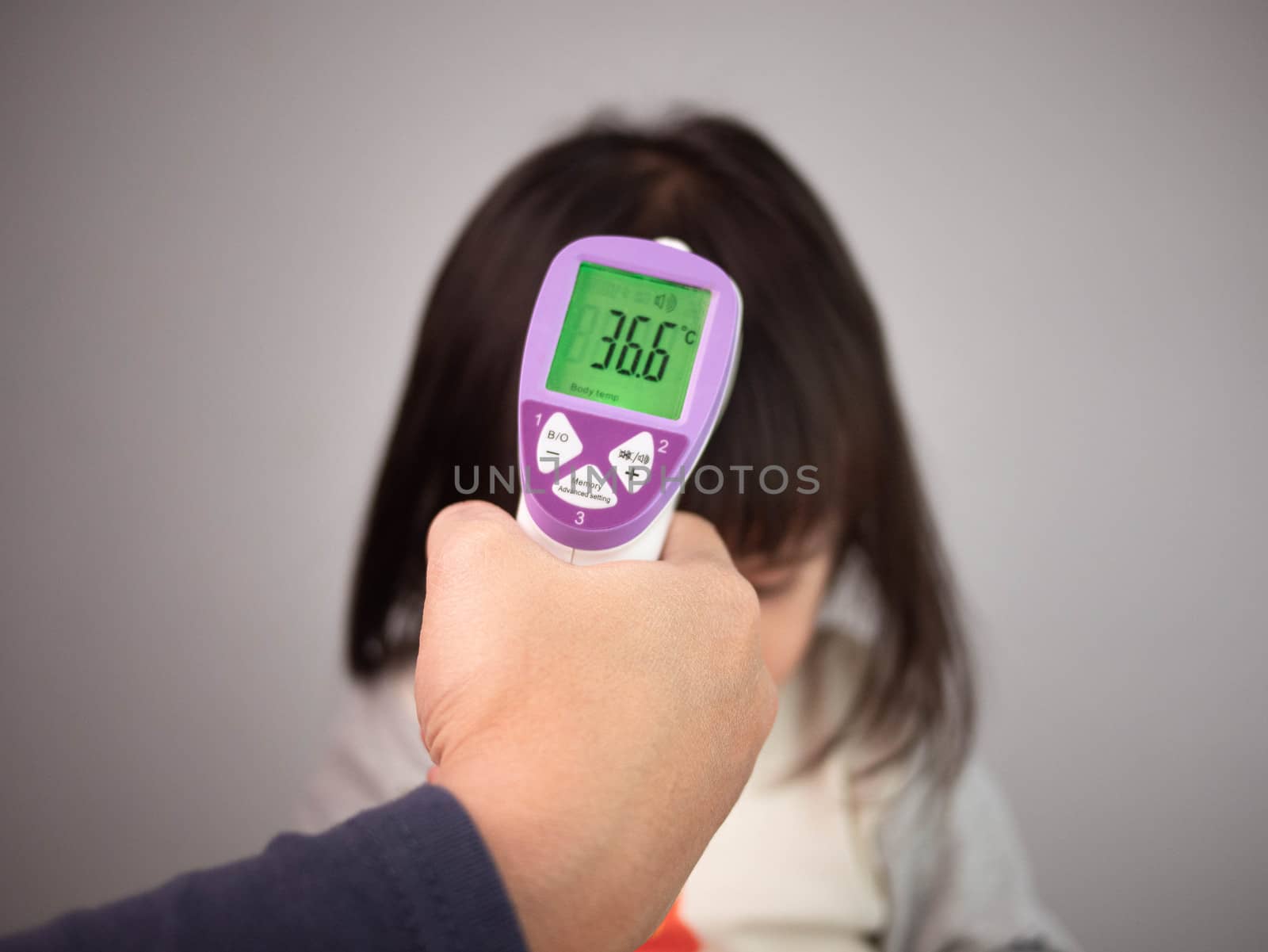 Close up of mother hand checking temperature of her sick daughte by TEERASAK