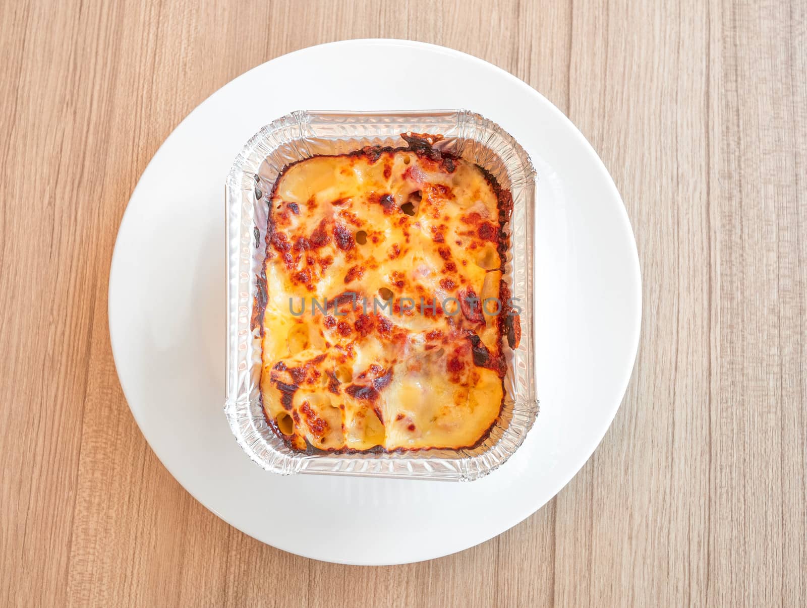 Macaroni with ham and cheese in a baking dish on wooden table. T by TEERASAK