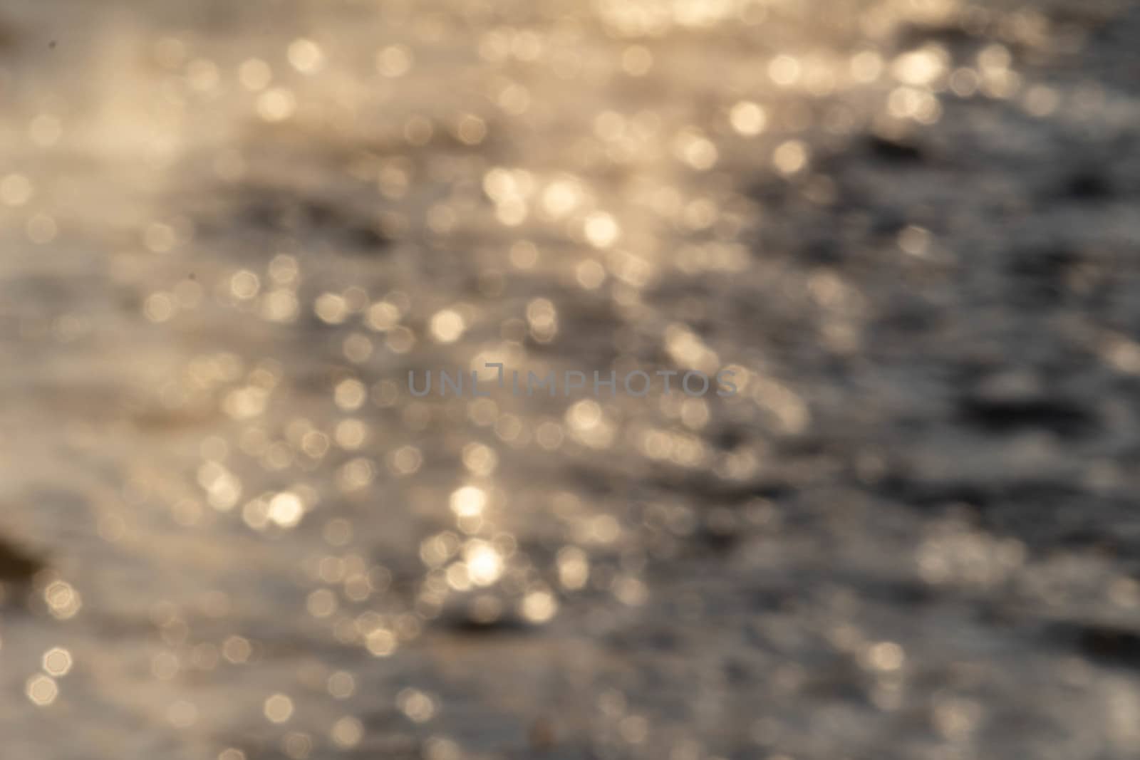 The defocused view of fresh river stream water slowly flowing through natural rock beach in the morning. Abstract nature background.