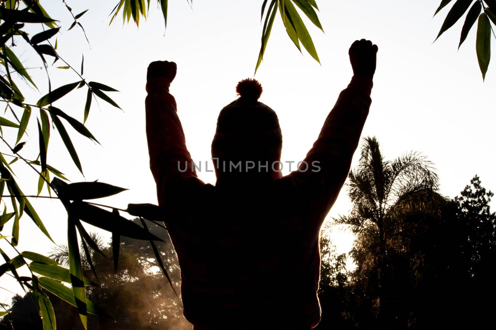 The silhouette of Happy beautiful young woman with raised arms enjoying the nature in winter time at sunrise background.