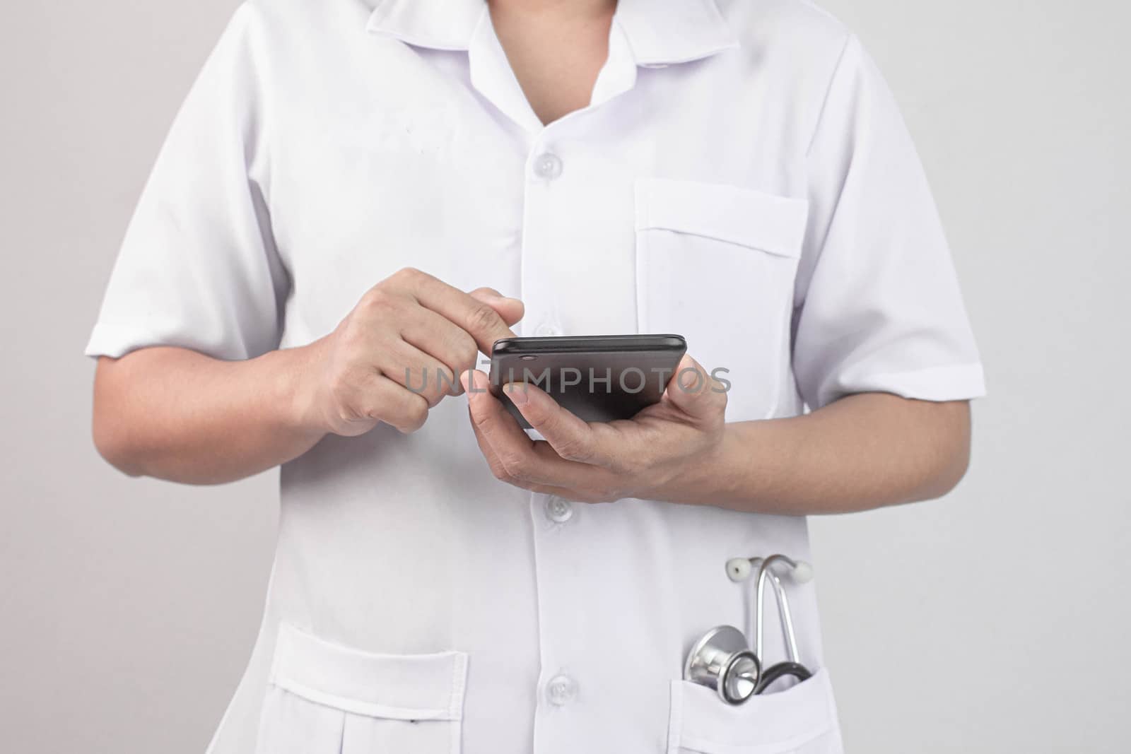 Confident young woman doctor using smartphone with stethoscope i by TEERASAK