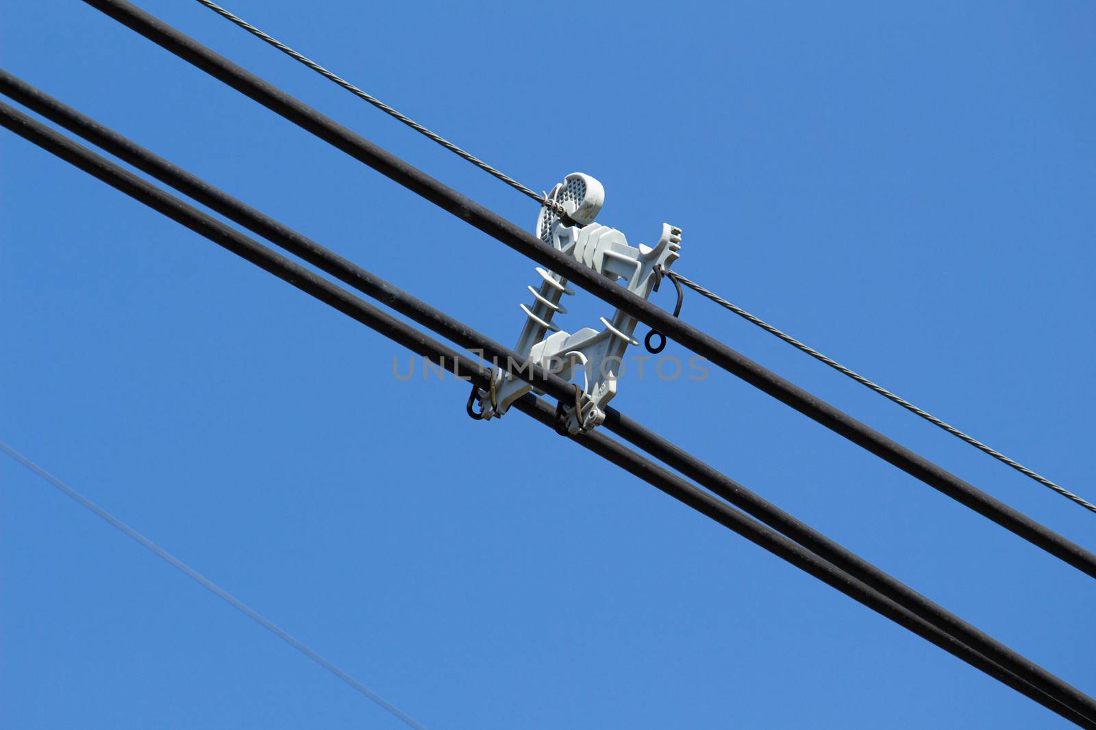 Electric cable wires with spacer damper on blue sky background.