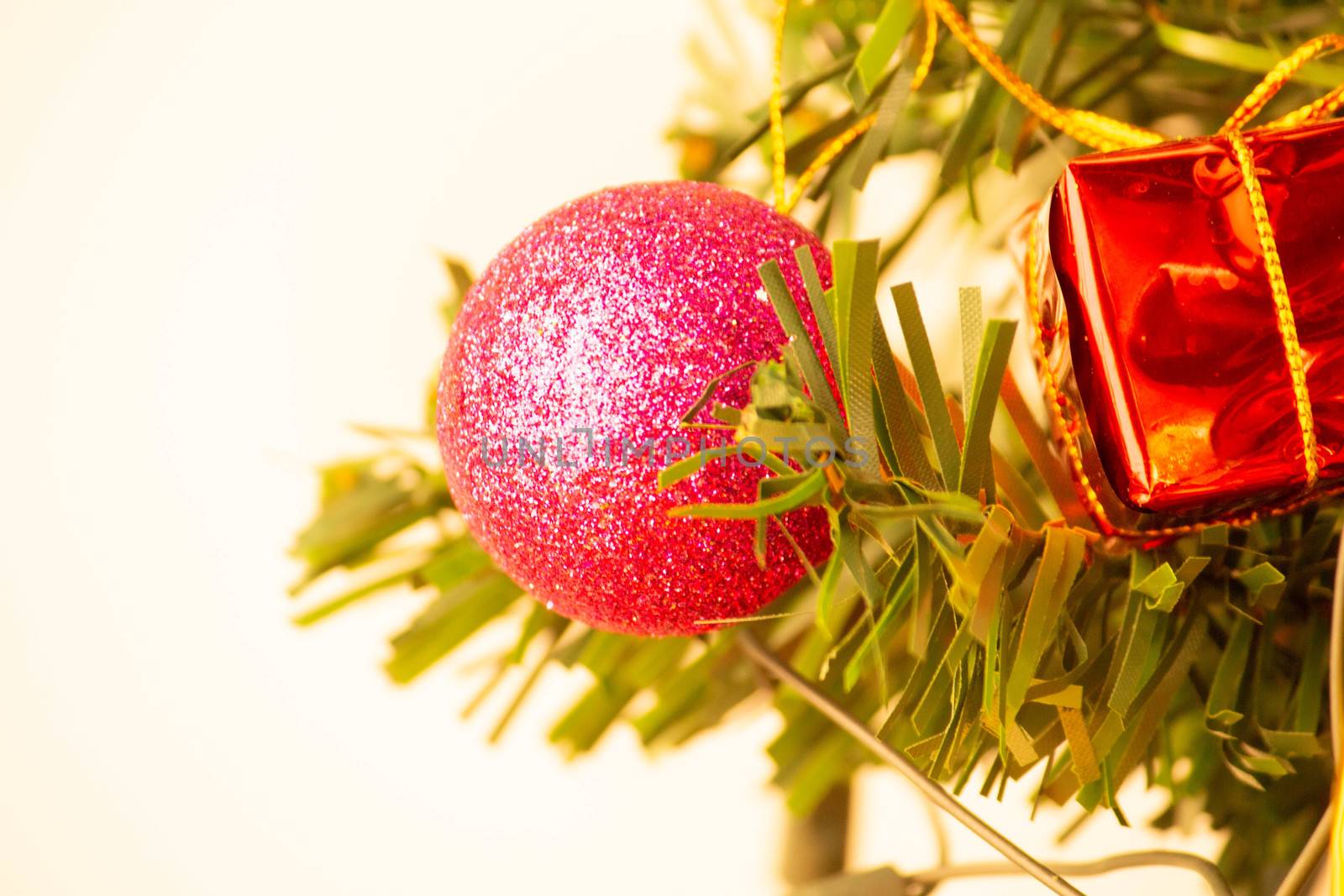 Close up of pink bauble hanging from a decorated Christmas tree  by TEERASAK