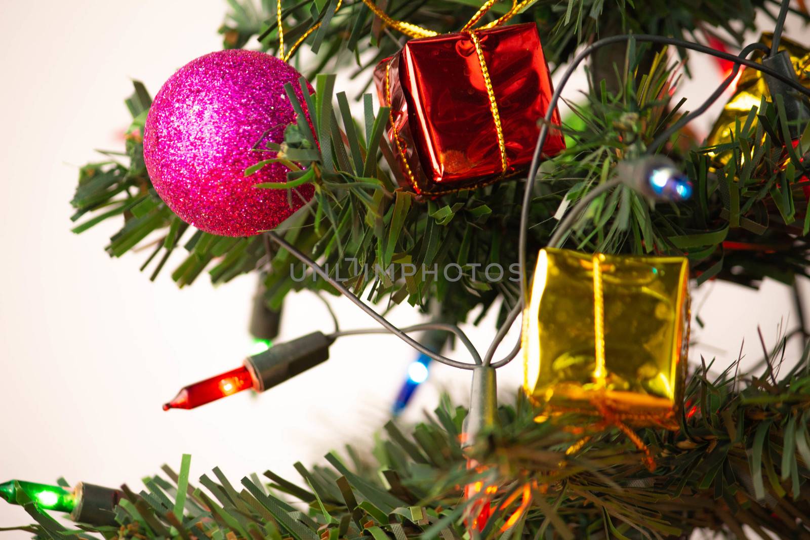 Close up of pink bauble hanging from a decorated Christmas tree  by TEERASAK
