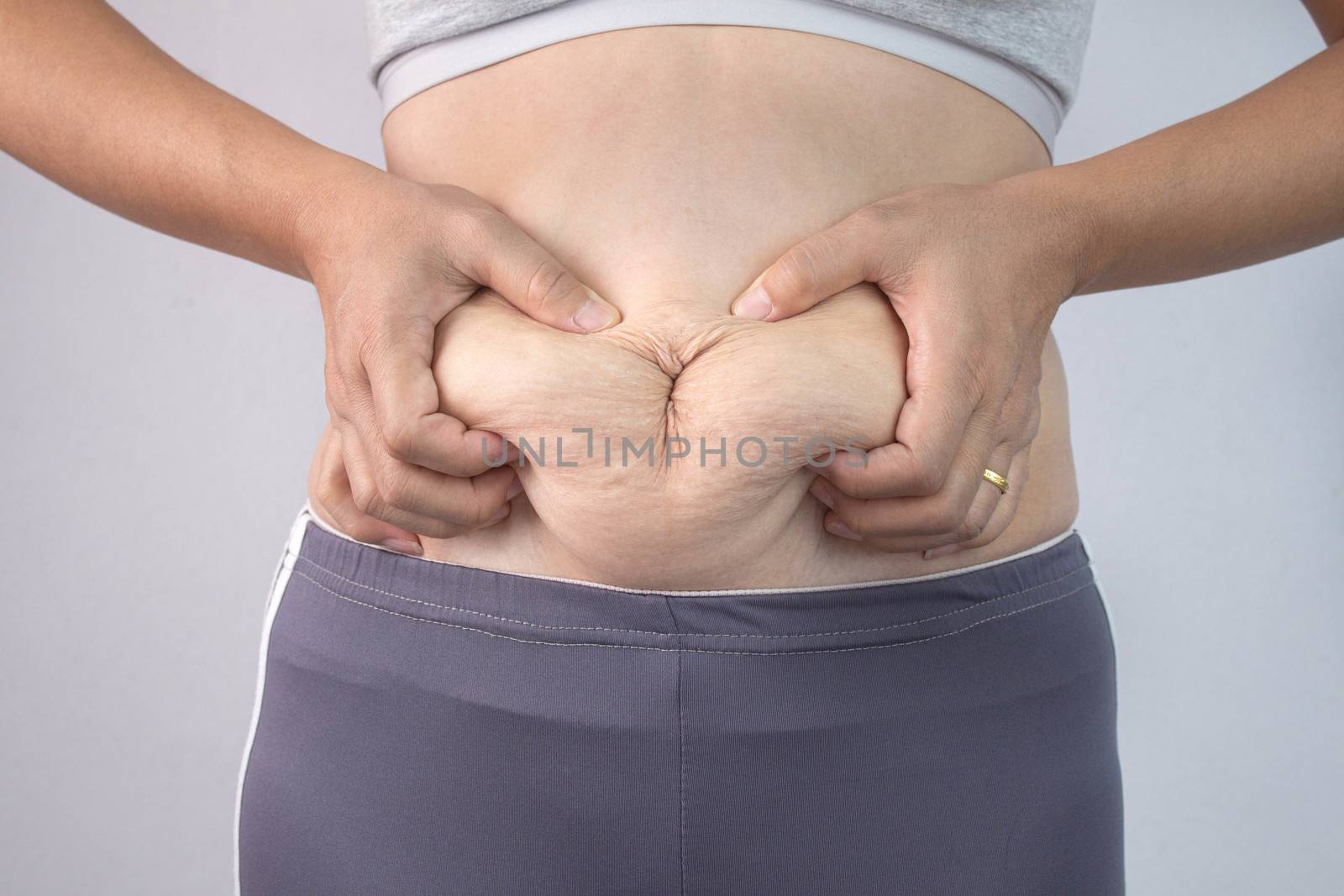 Close-up of woman's hand pinching excessive belly fat isolated o by TEERASAK