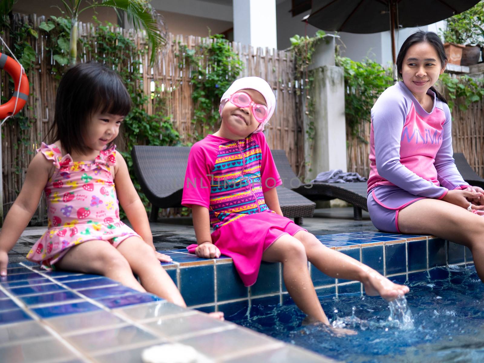 Happy Asian family enjoying summer vacation in swimming pool at by TEERASAK