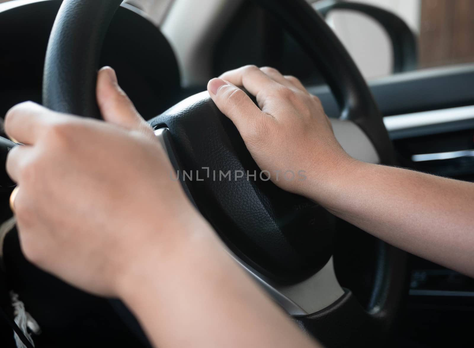 Close up inside vehicle of female hand pushing on steering wheel by TEERASAK