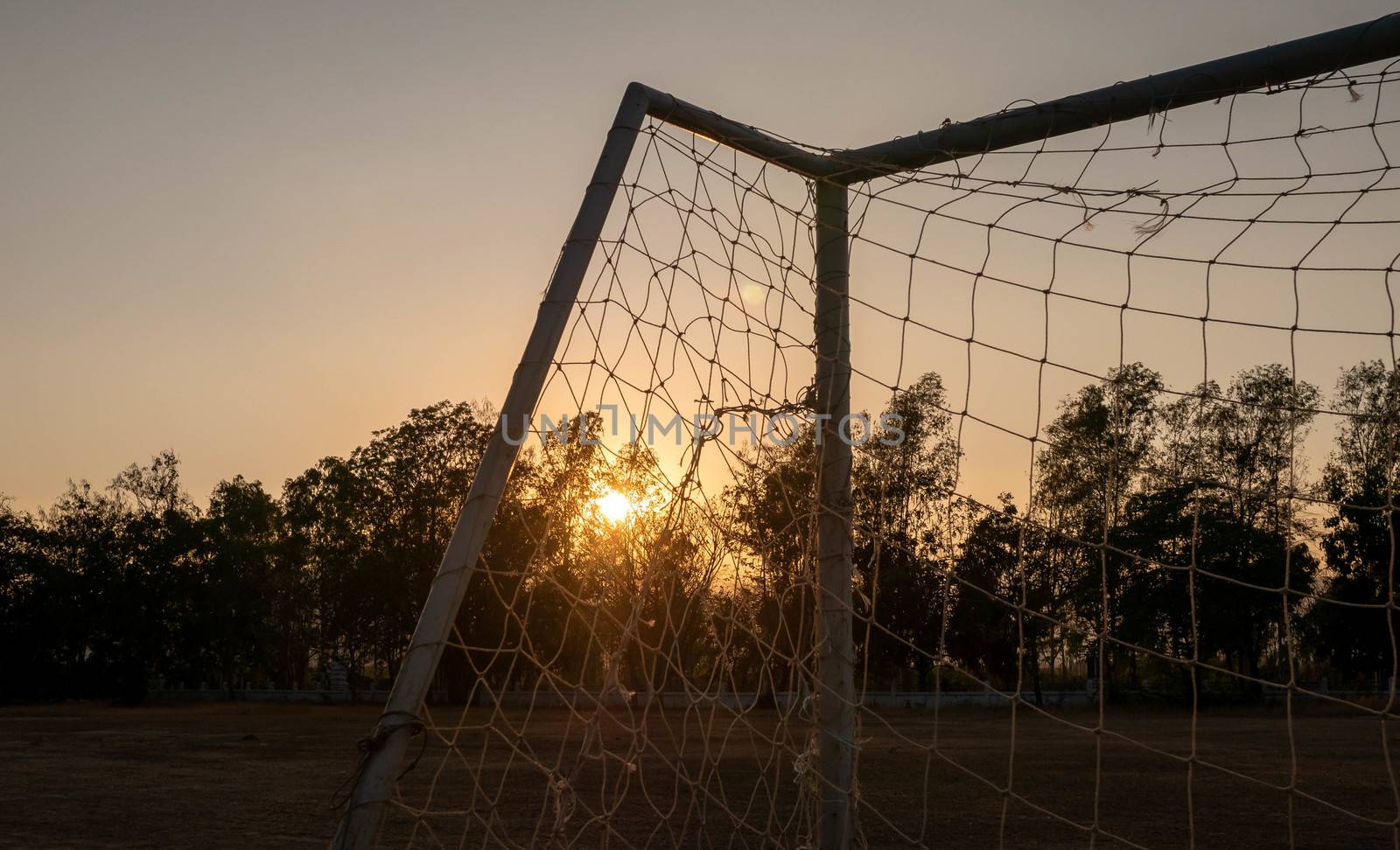 Football goal with sunset light background in the public stadium.