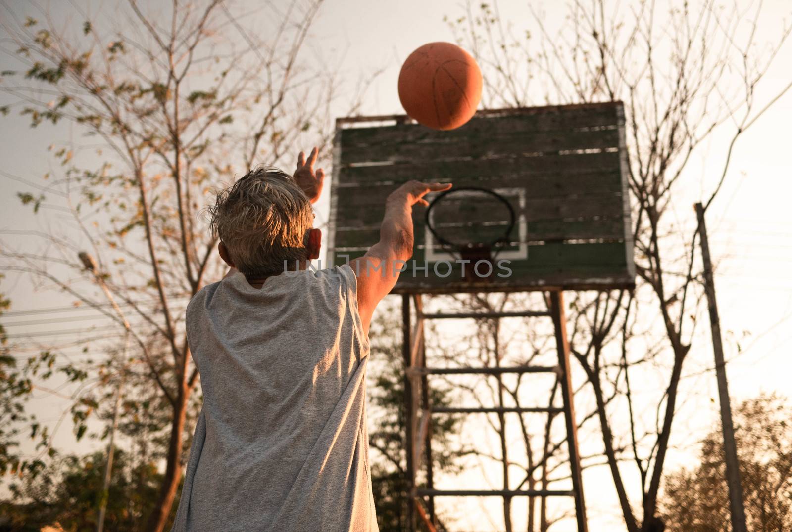 Asian elderly men playing basketball on playground on summer day. Healthy lifestyle and Healthcare concept. by TEERASAK