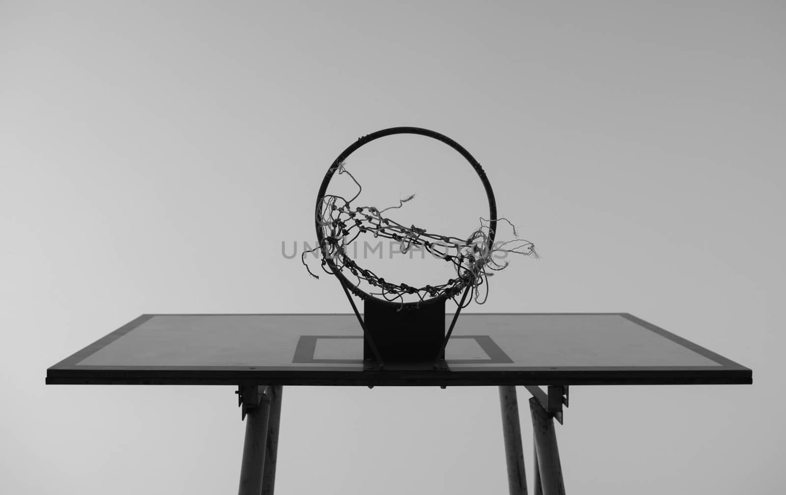 Black and white tone of Old basketball hoop on sky background in the public stadium. by TEERASAK