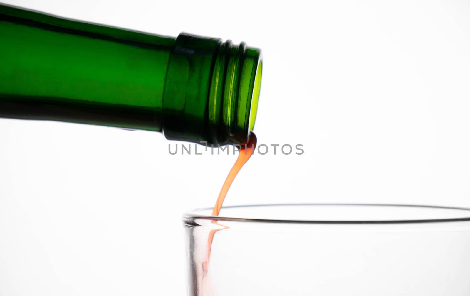 Close up of pouring fruit juice from green bottle into glass, isClose up of pouring fruit juice from green bottle into glass, isolated on white background. by TEERASAK