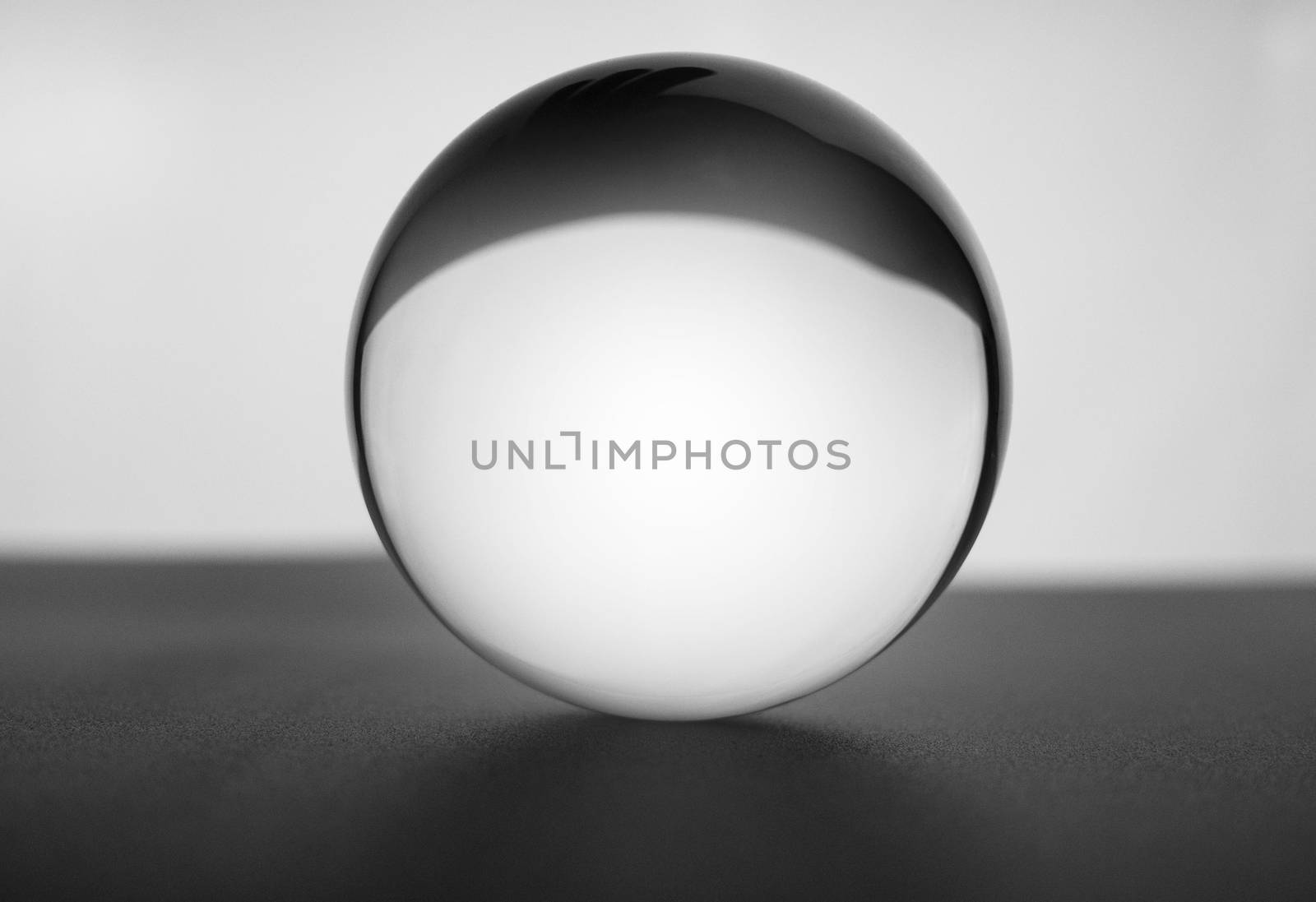 Crystal glass ball sphere transparent on grey gradient background.