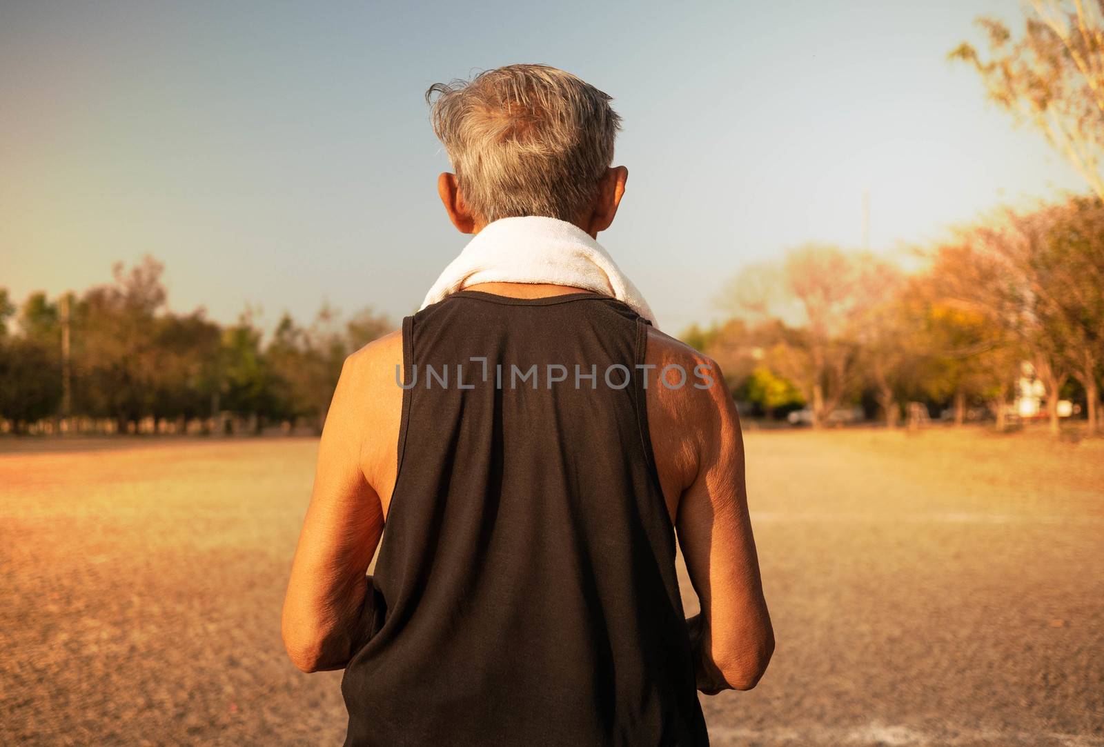 Rear of Asian senior man jogging in the park for good health. Healthcare concept. by TEERASAK