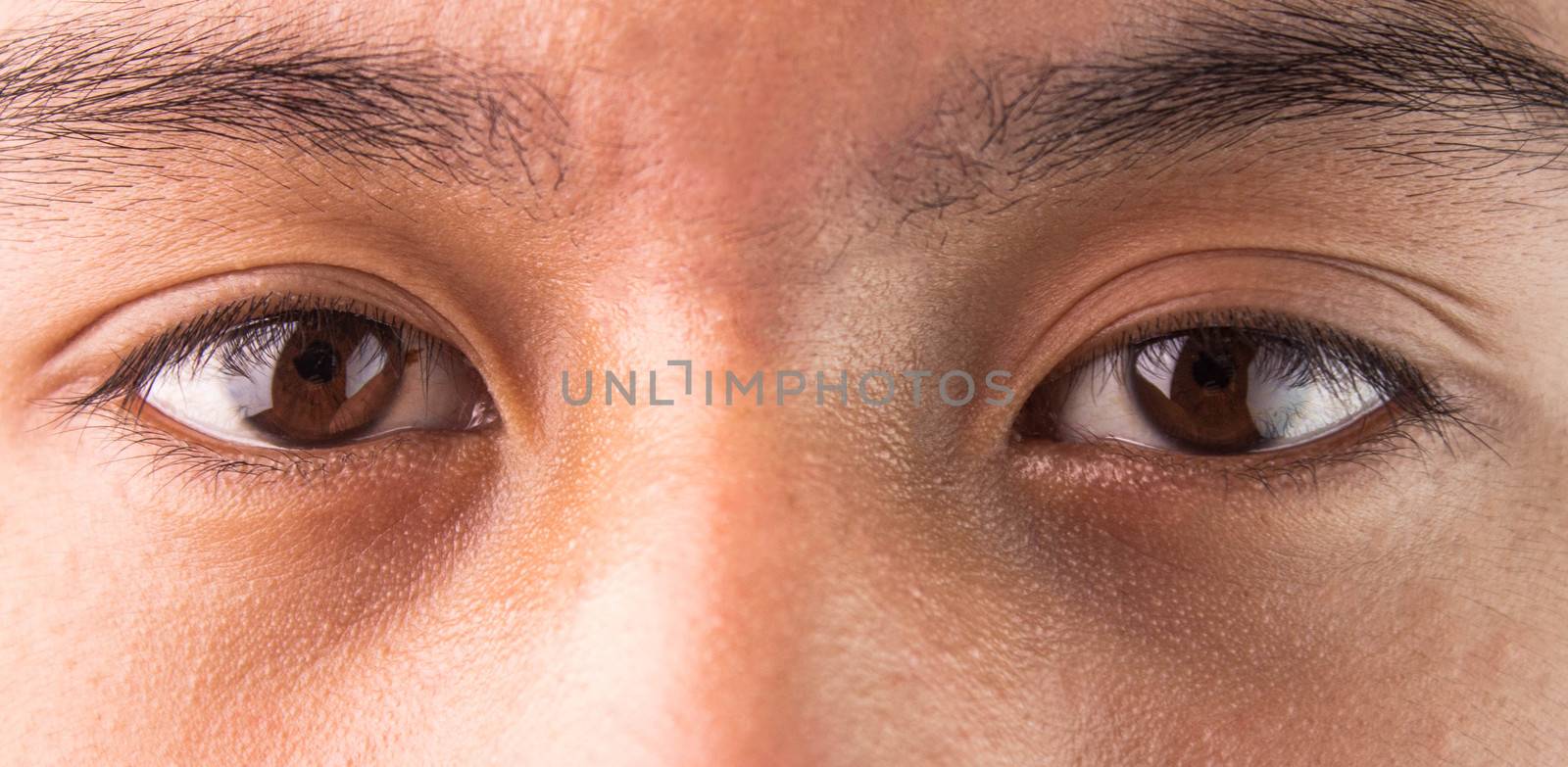 Close-up of Asian teenage guy brown eye with looking straight to by TEERASAK