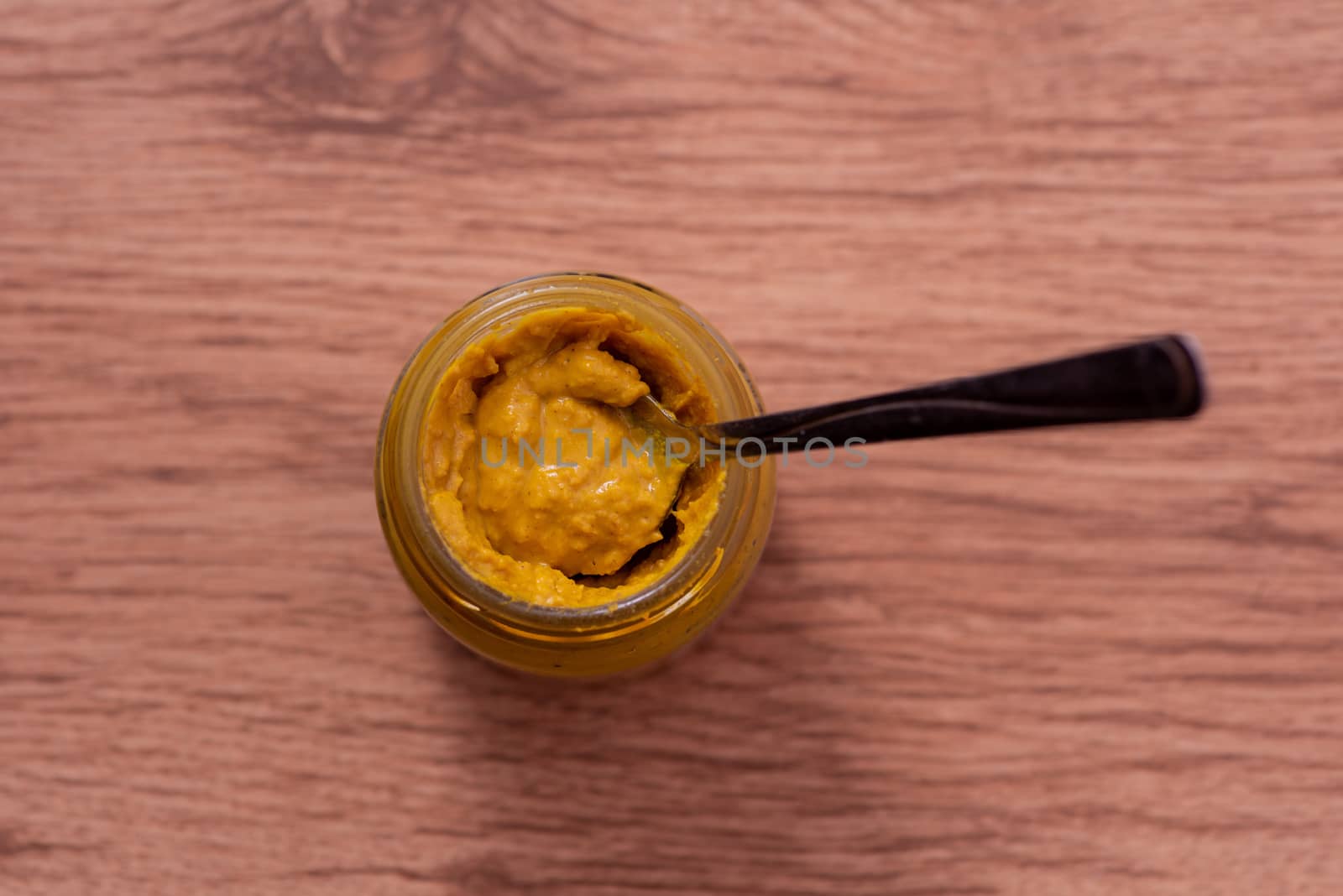 Mustard with spoon in shot from above