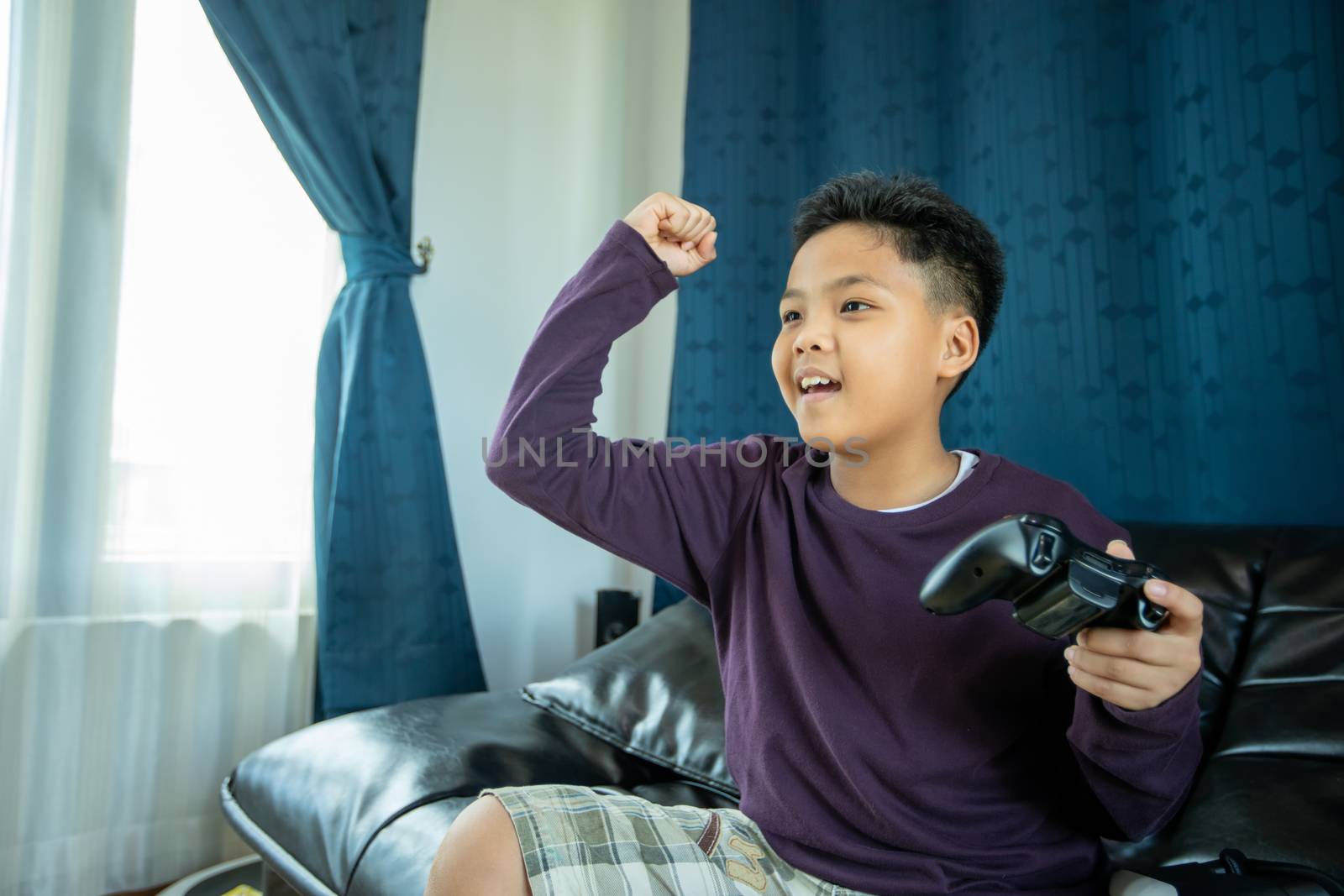 Asian boy enjoy playing video games together with video joystick with excite and very fun in the living room at home